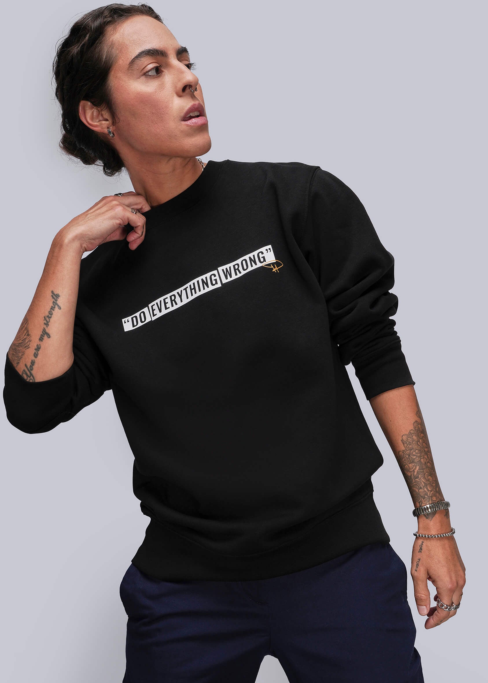 S=Person wearing a black sweatshirt with text, standing against a plain background