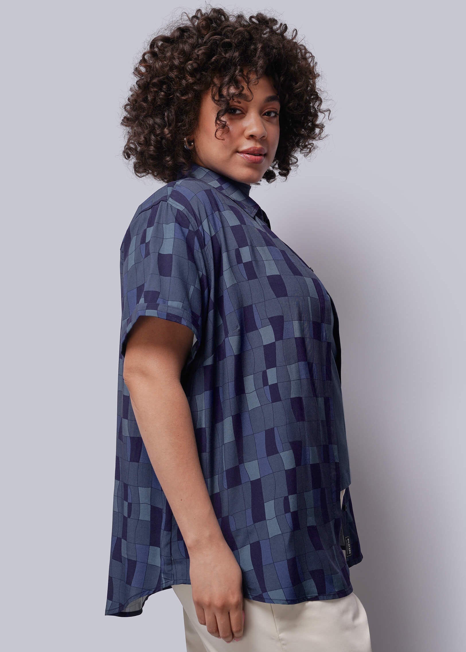 1X=Person wearing a blue patterned shirt against a plain background
