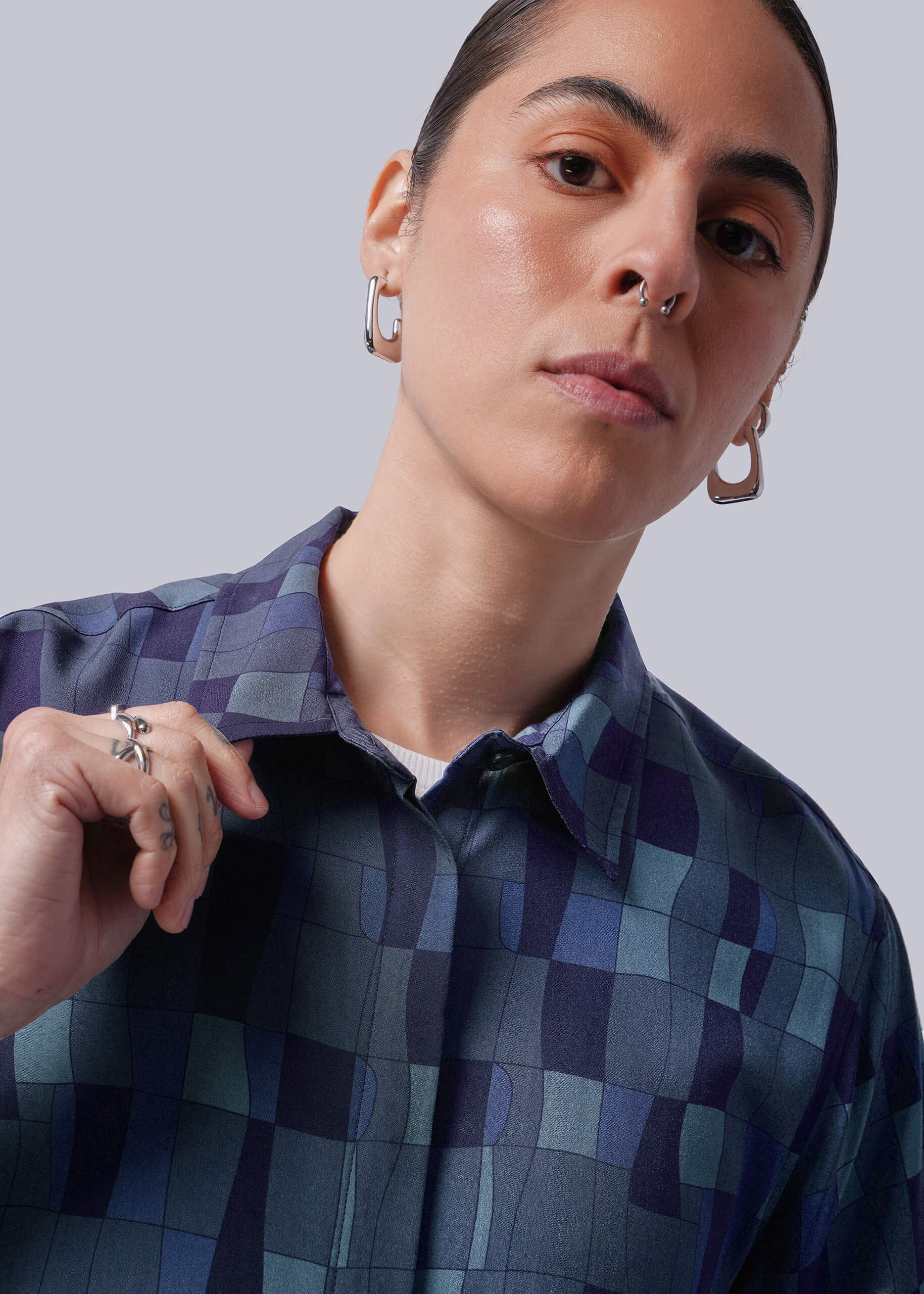 S=Close up of person wearing a blue patterned shirt against a plain background