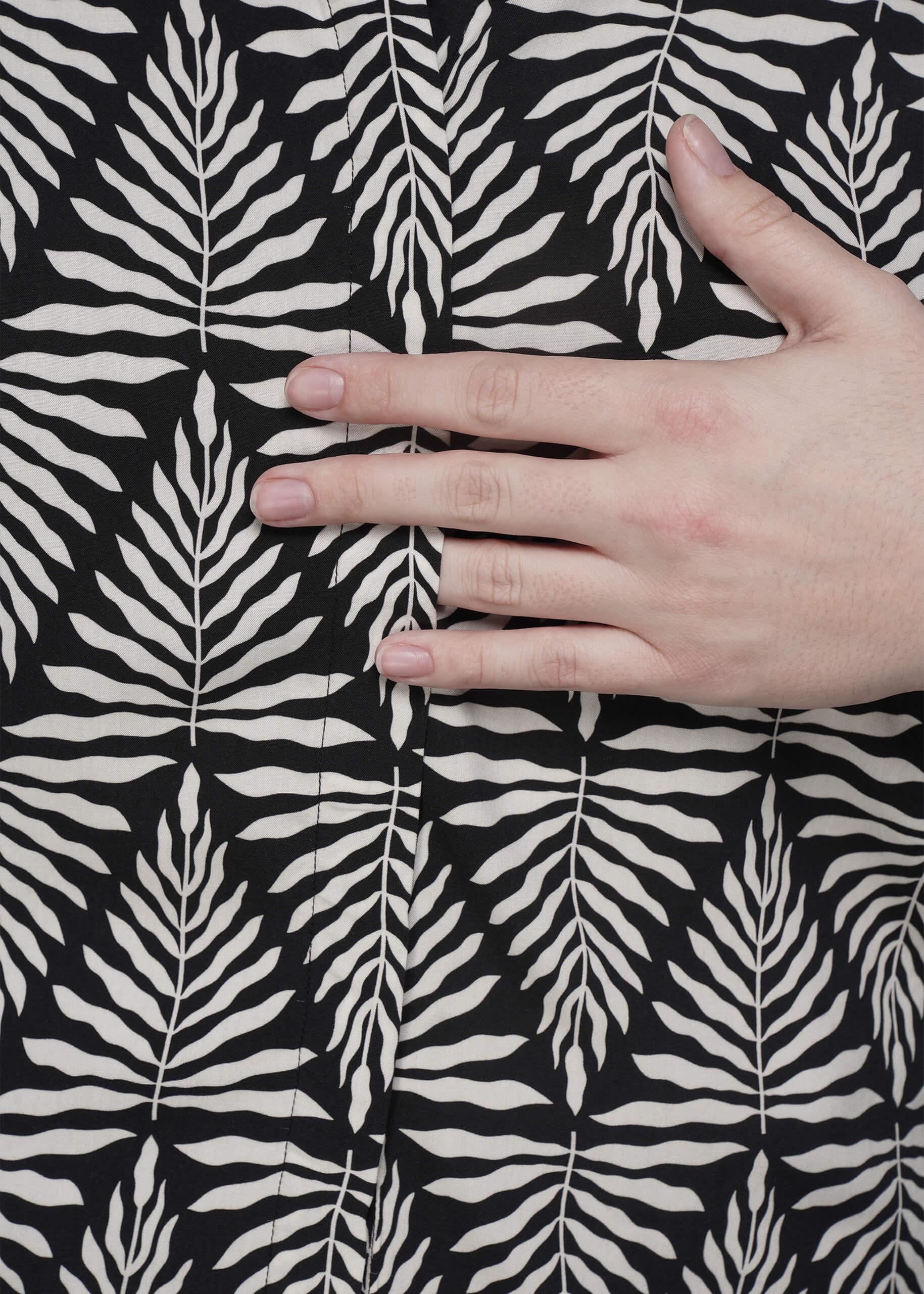 S=Hand touching black fabric with white leaf pattern