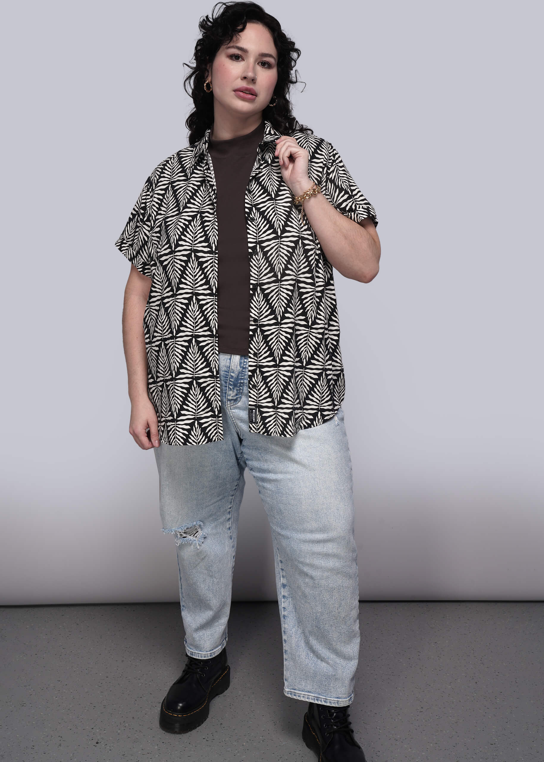 1X=Person wearing a patterned shirt and jeans against a plain background