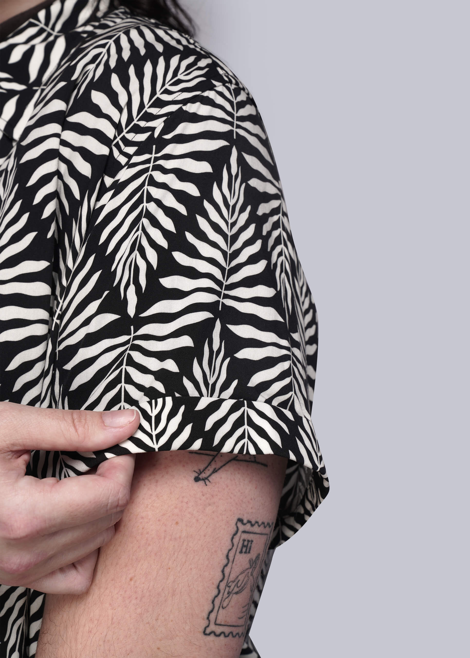 1X=Person wearing a black and white leaf patterned shirt with a plain background