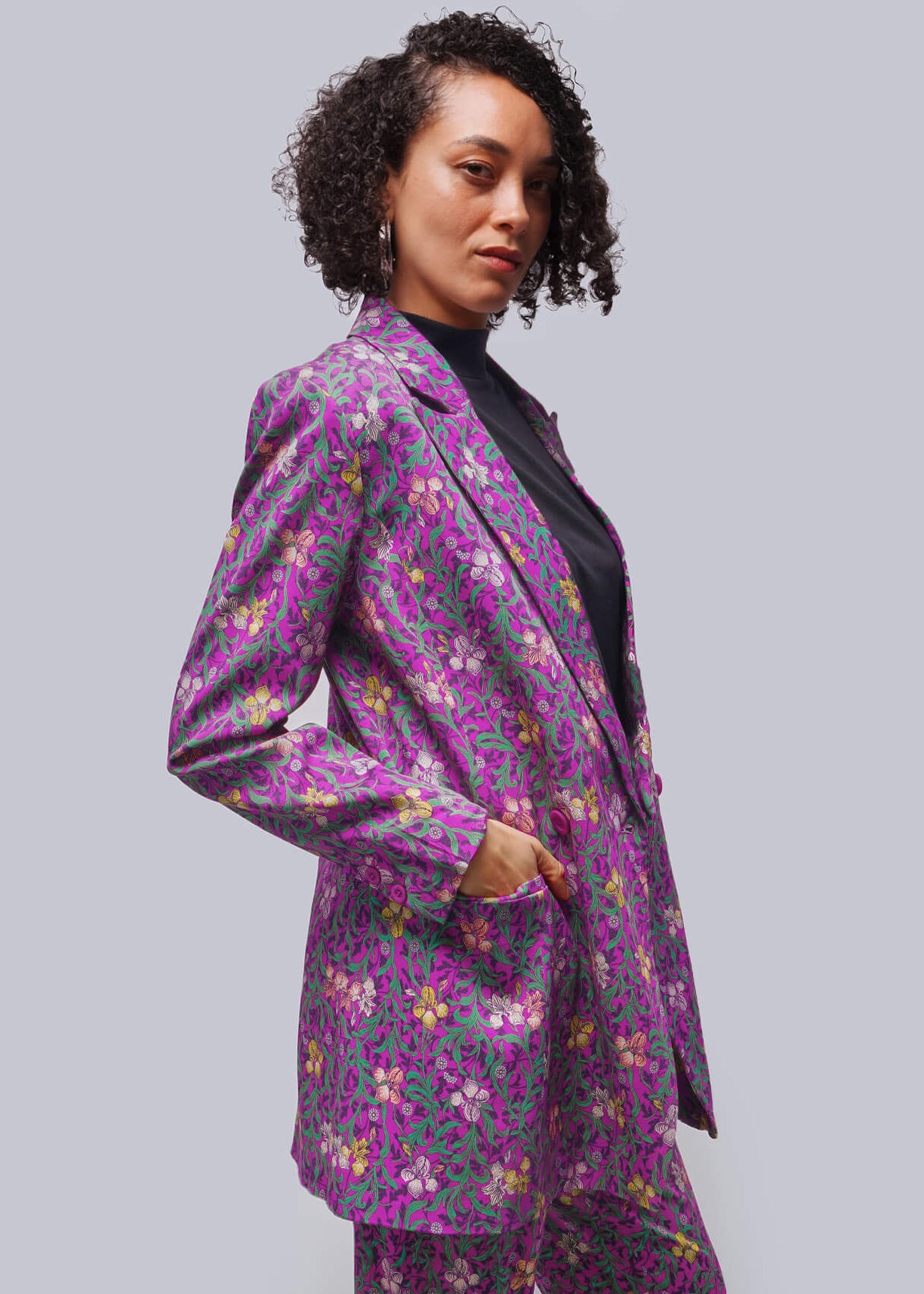 S=Person wearing a purple floral suit against a plain background