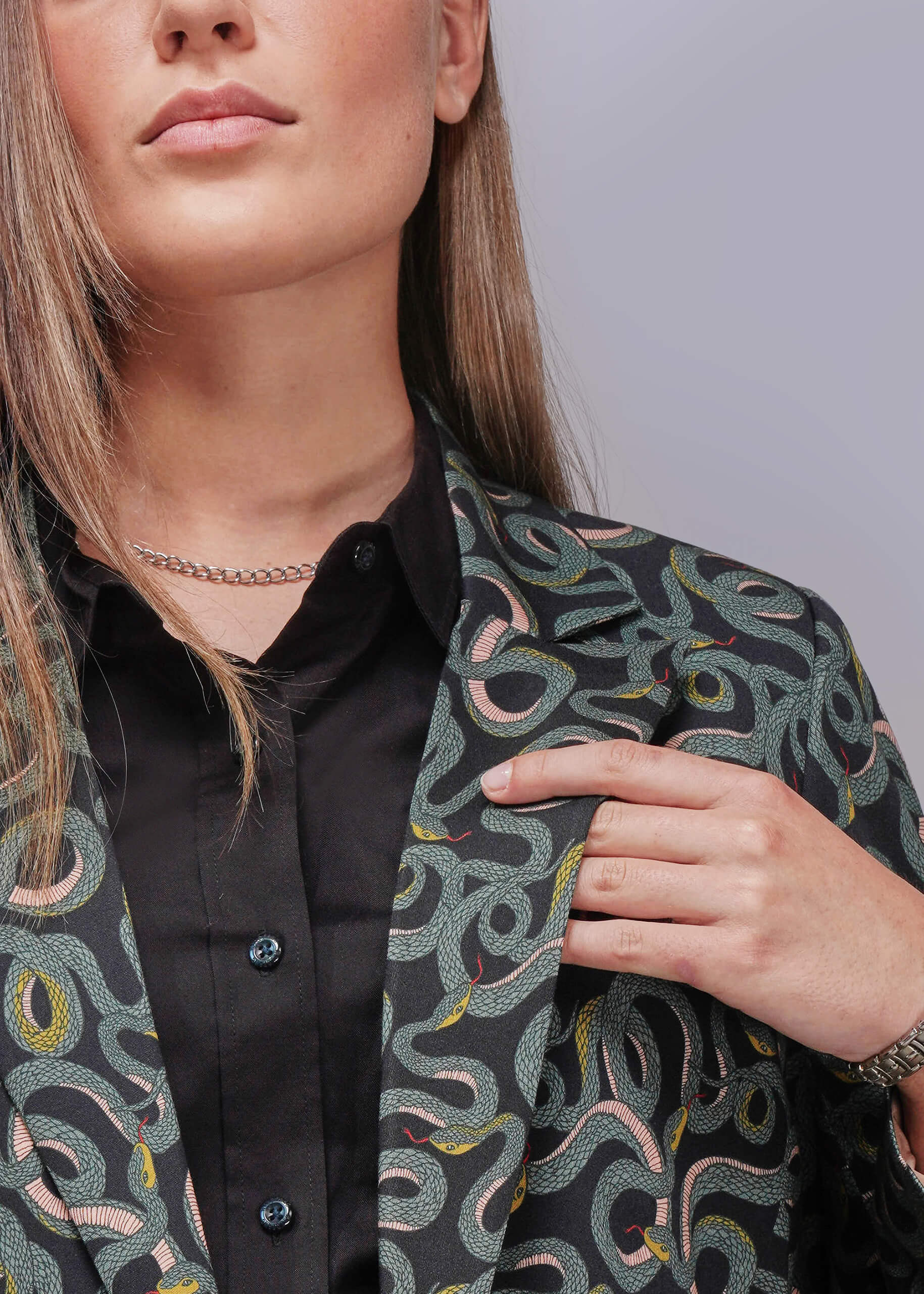 Person wearing a patterned jacket over a black shirt on a light gray background