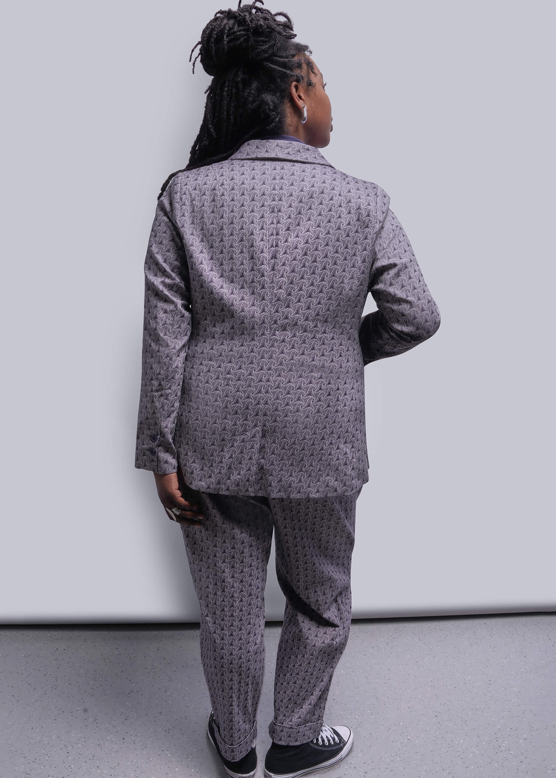 1X=Person wearing a gray patterned suit against a white background