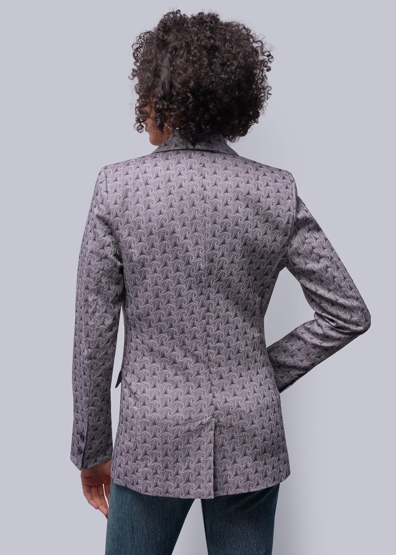 S=Person wearing a patterned gray blazer on a light gray background