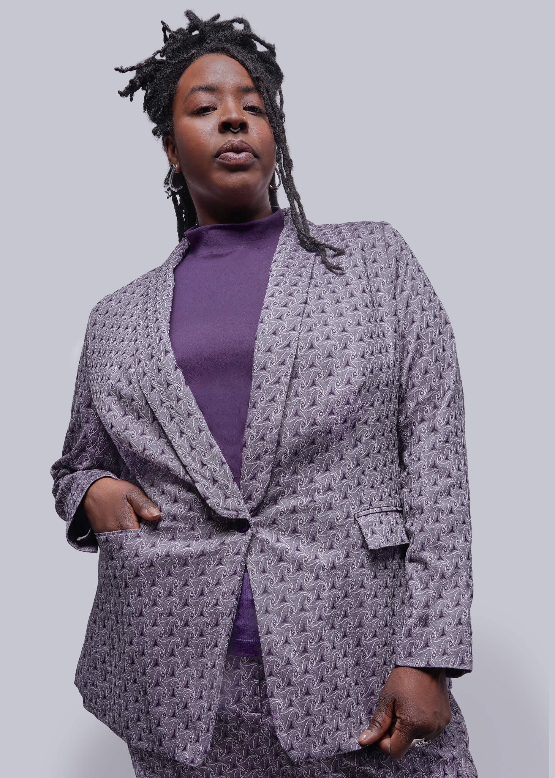 1X=Person wearing a purple textured blazer over a purple top on a plain background