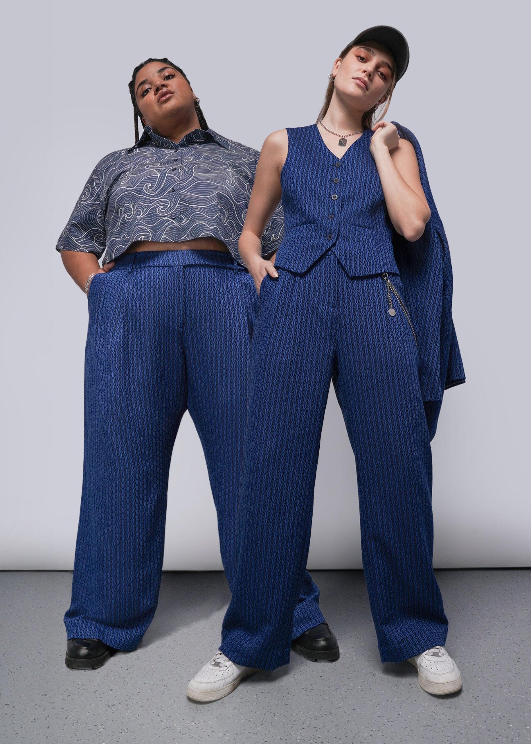 Two people wearing matching blue suits against a plain background