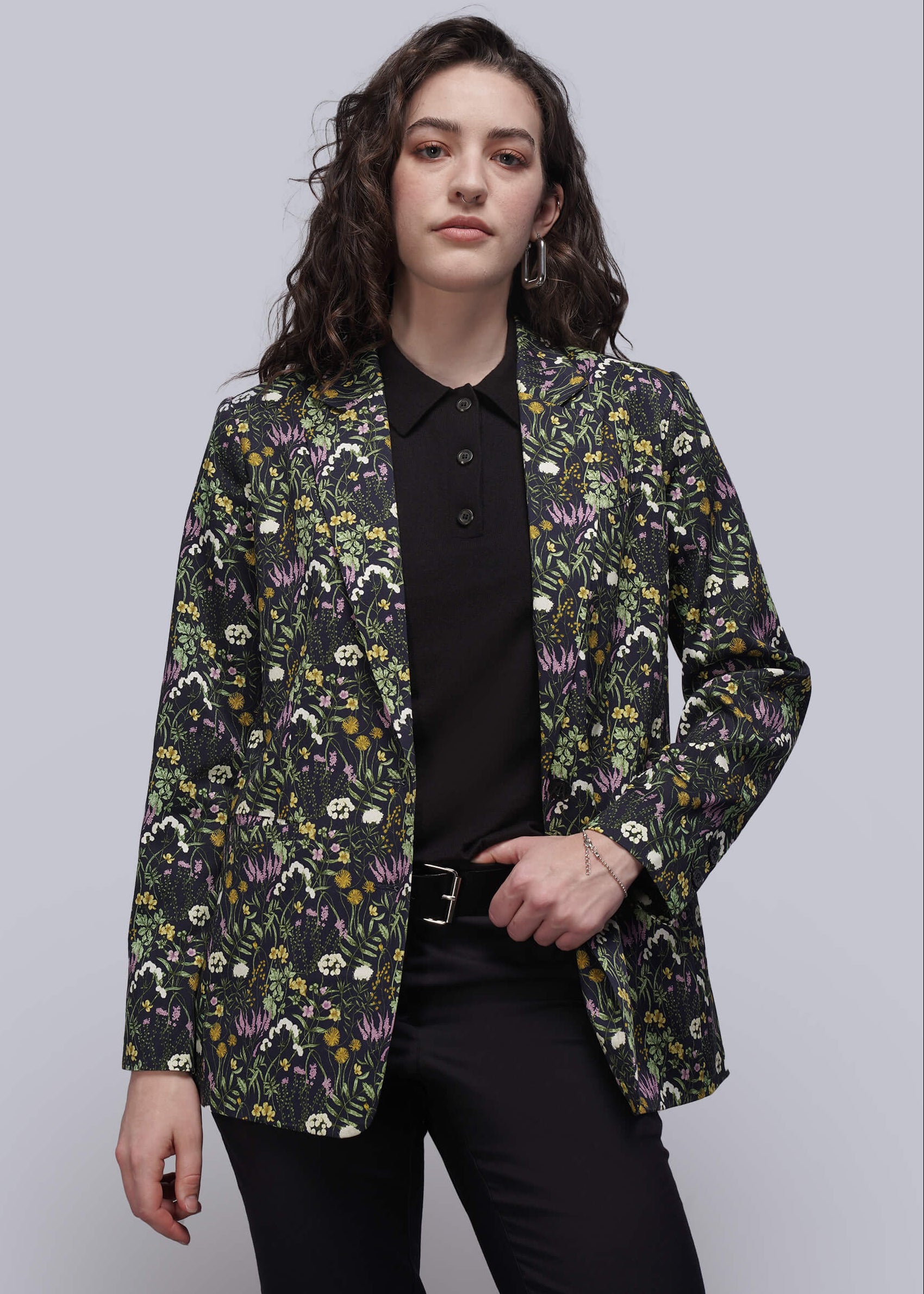 S=Person wearing a floral patterned blazer over a black shirt and pants on a plain background
