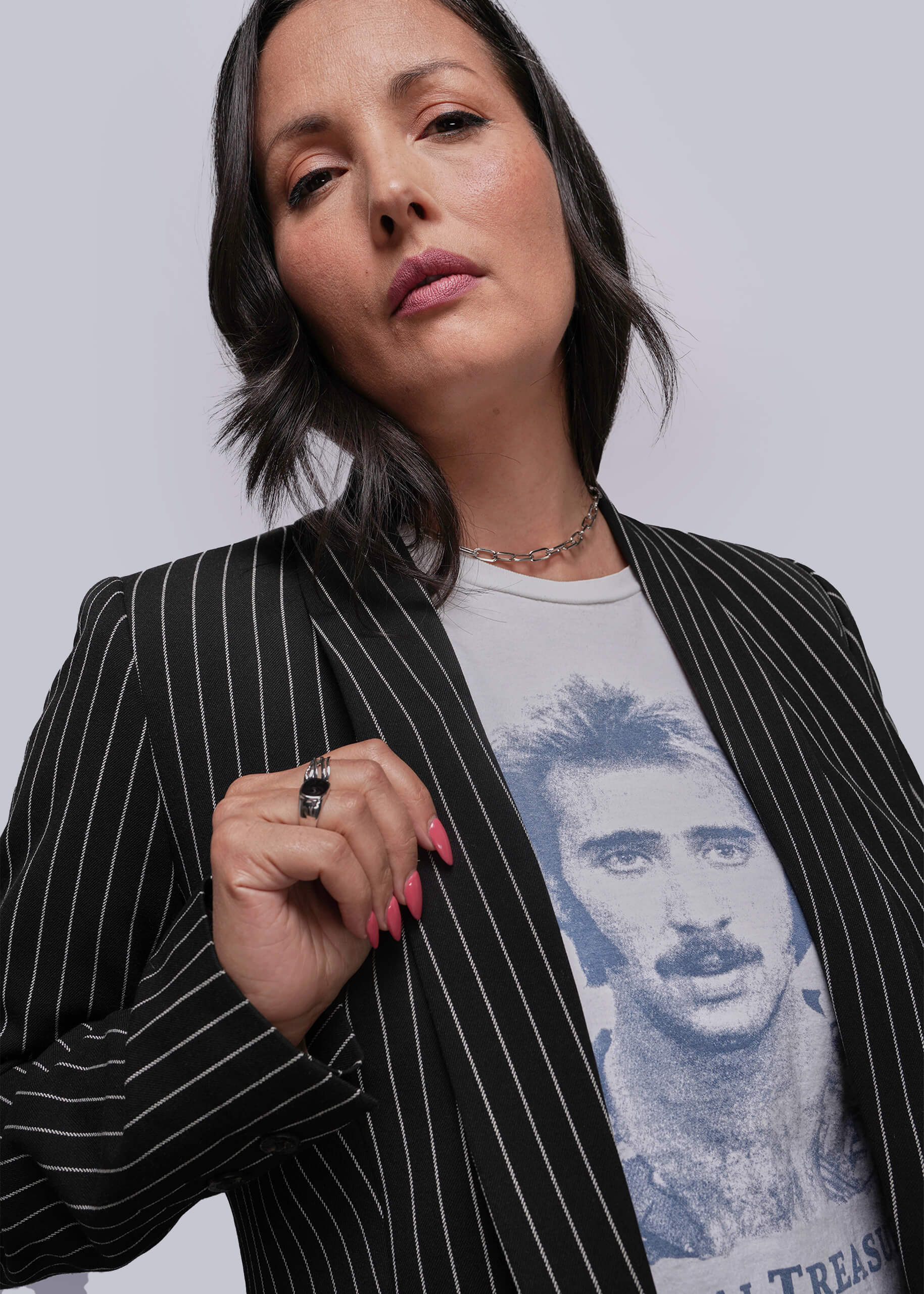 Woman wearing a black pinstripe blazer over a graphic t-shirt with a plain background