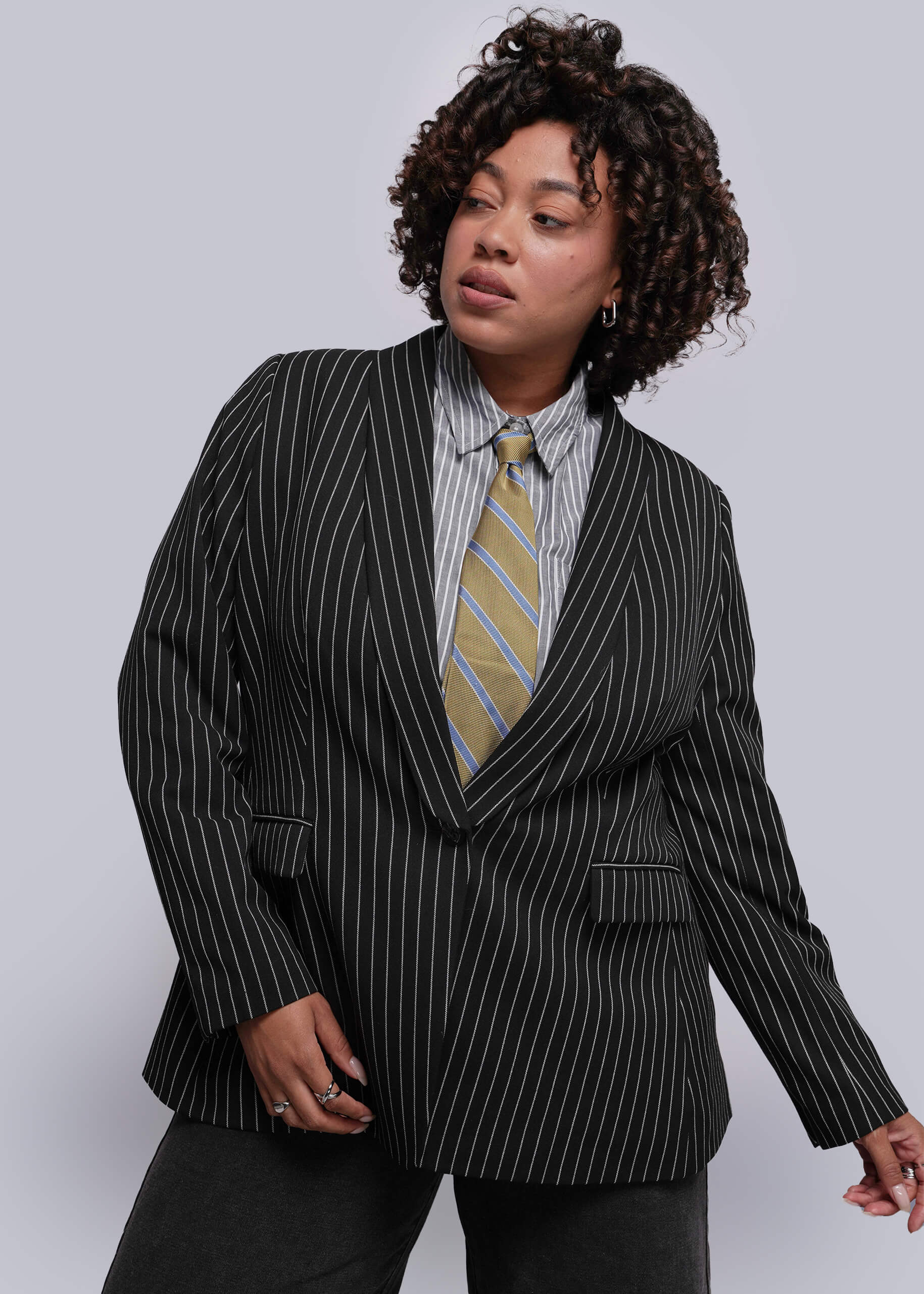 1X=Person wearing a black pinstripe suit with a striped tie against a plain background