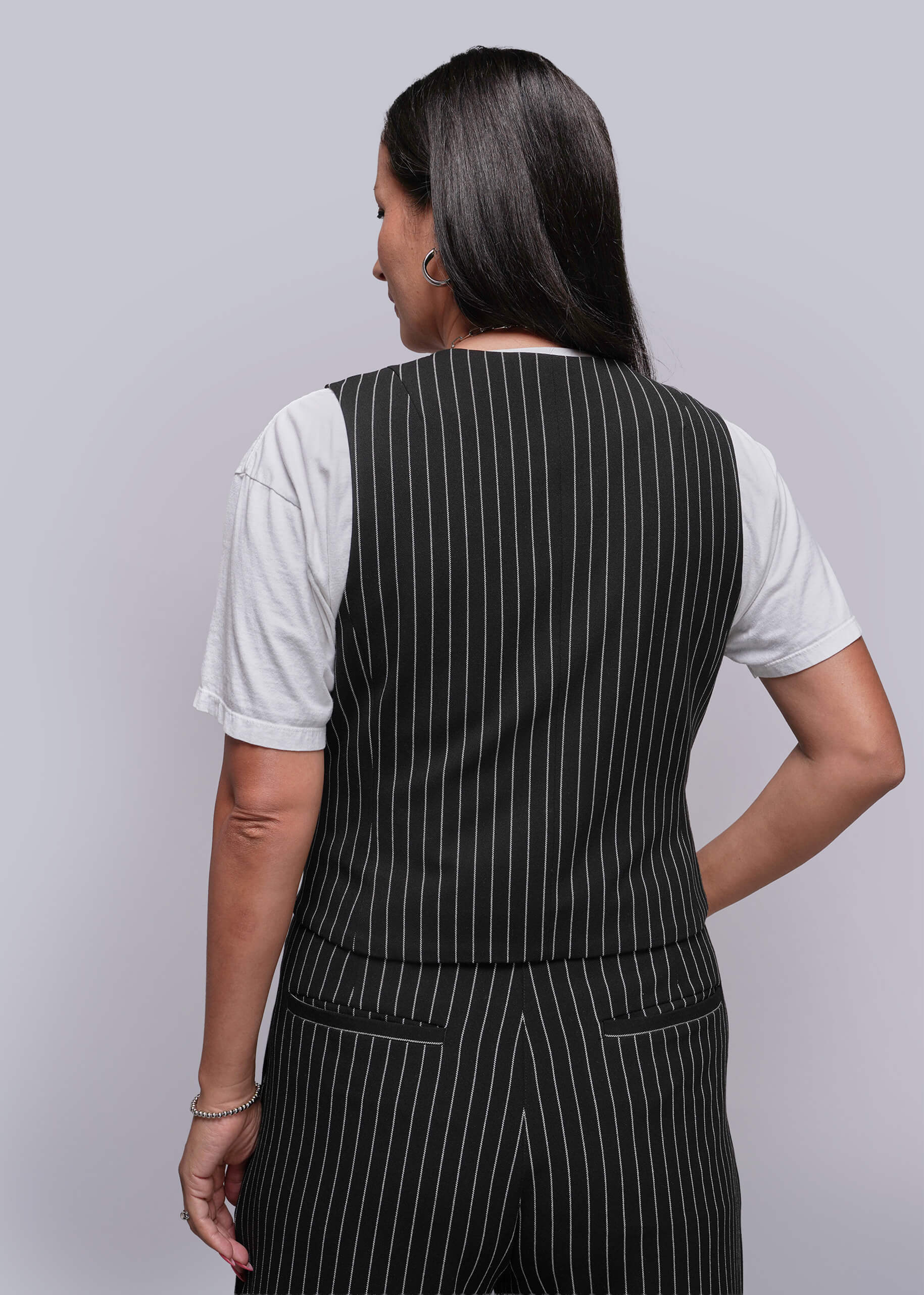 S=Person wearing a black pinstripe vest over a white shirt on a gray background