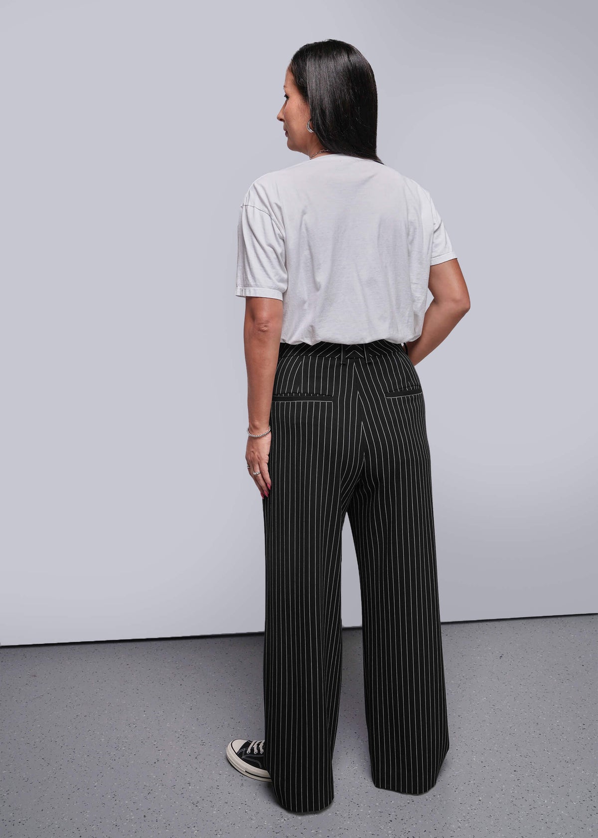 S=Person wearing a white shirt and black pinstripe pants against a plain background