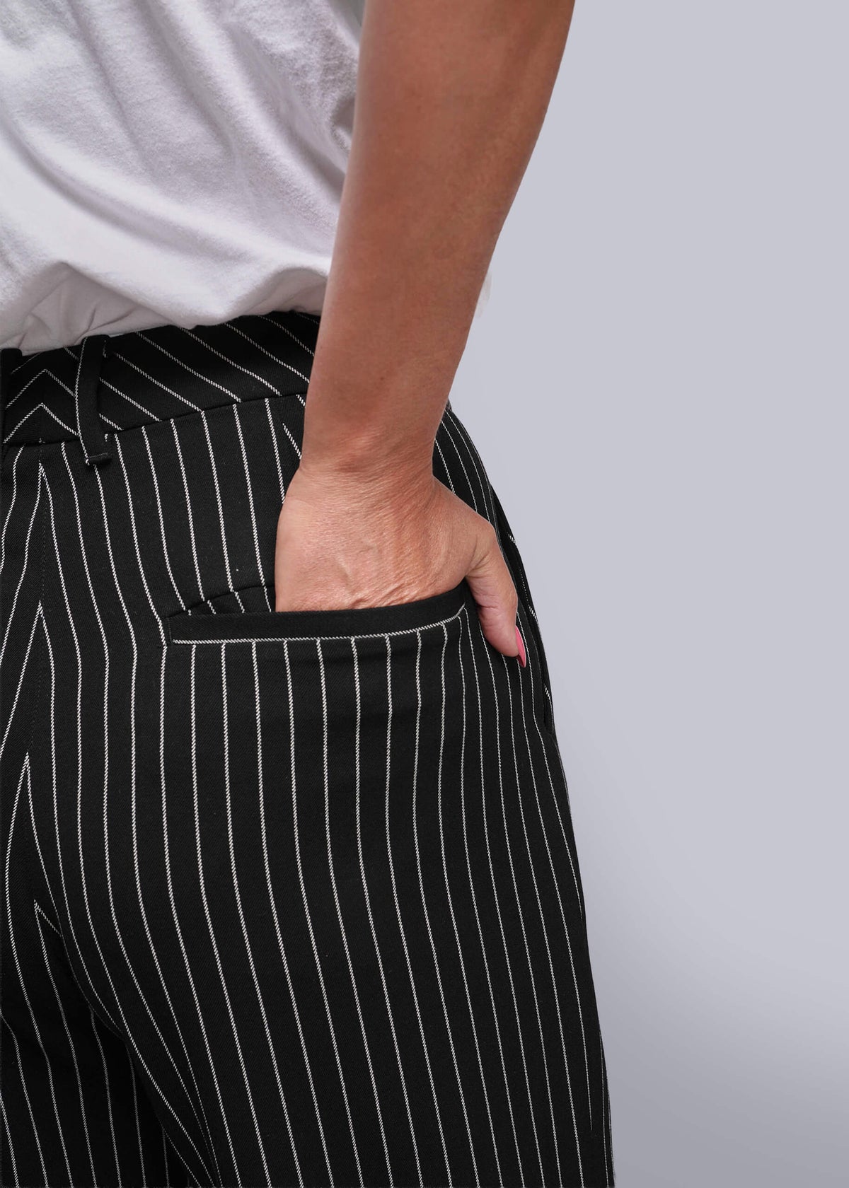 S=Person wearing black pinstripe pants with a white background