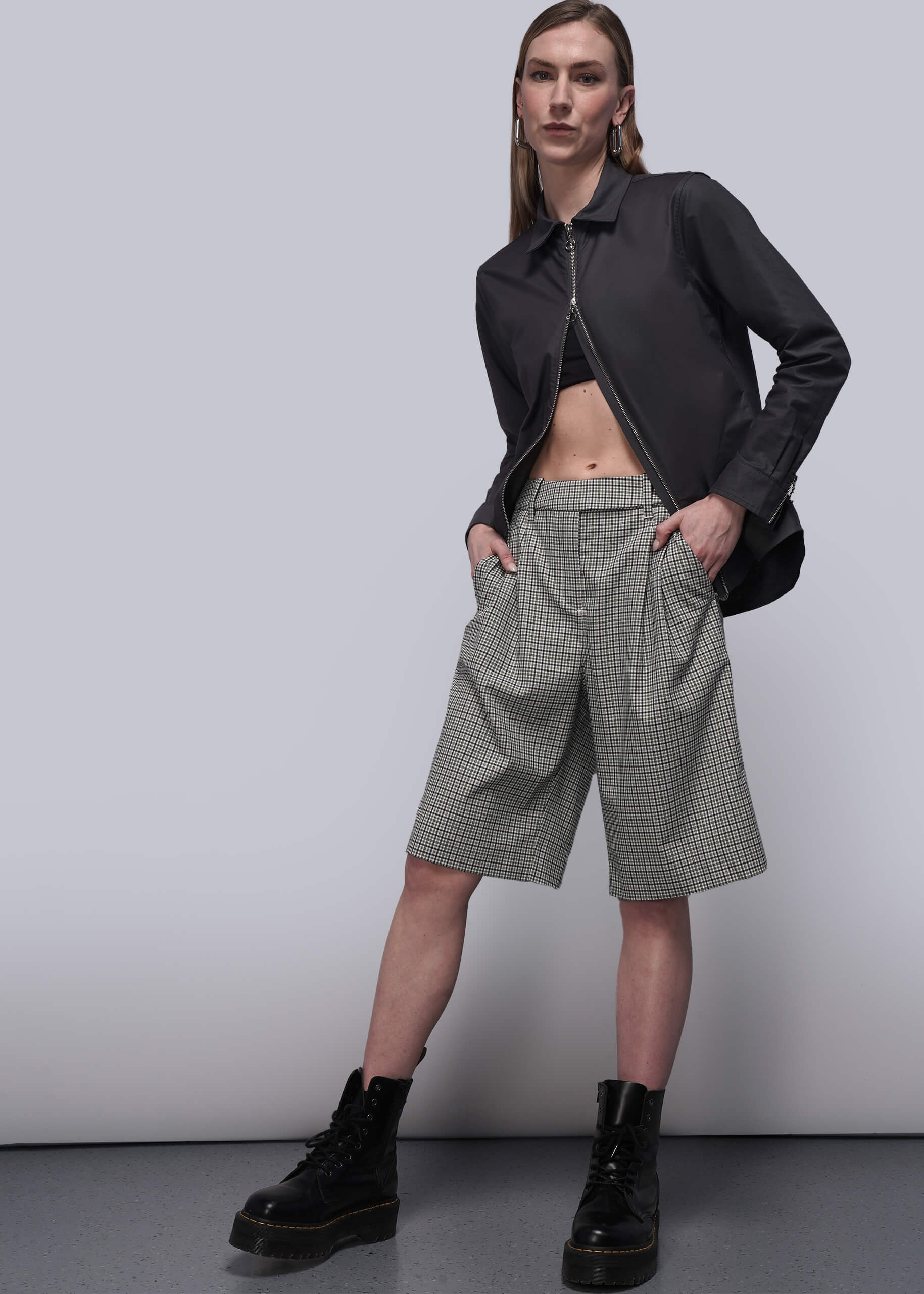 S=Person wearing a black top and checkered shorts against a plain background