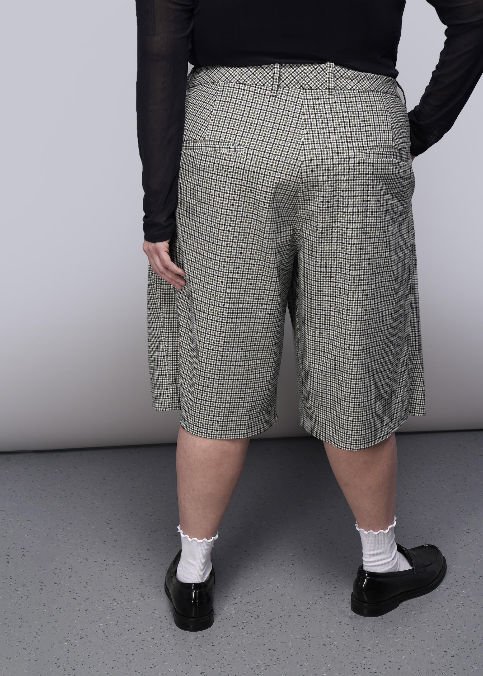 1X=Person wearing checkered shorts with a plain background