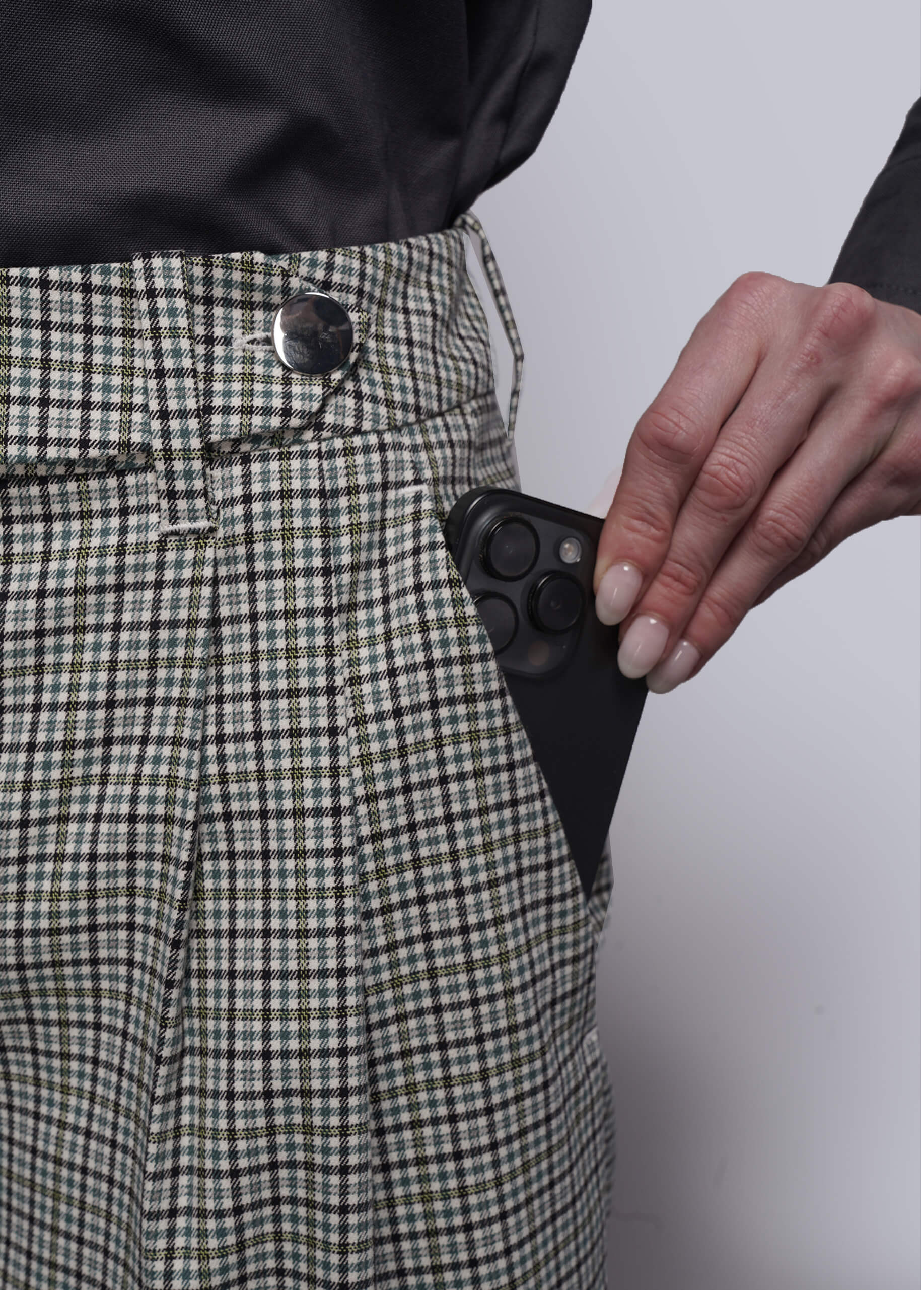 S=Person wearing checkered pants with a hand holding phone in pocket