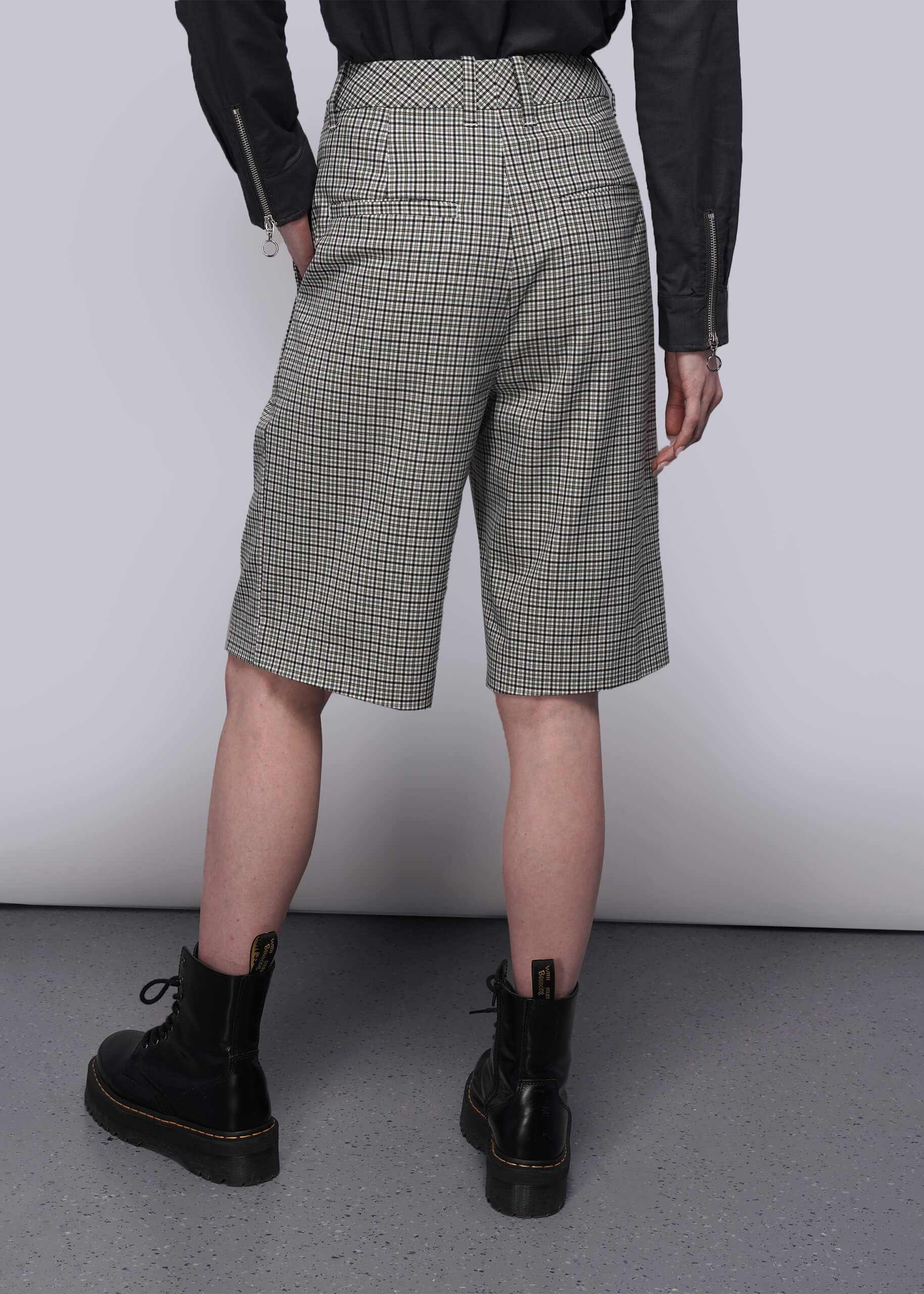 S=Person wearing checkered shorts and black boots on a plain background