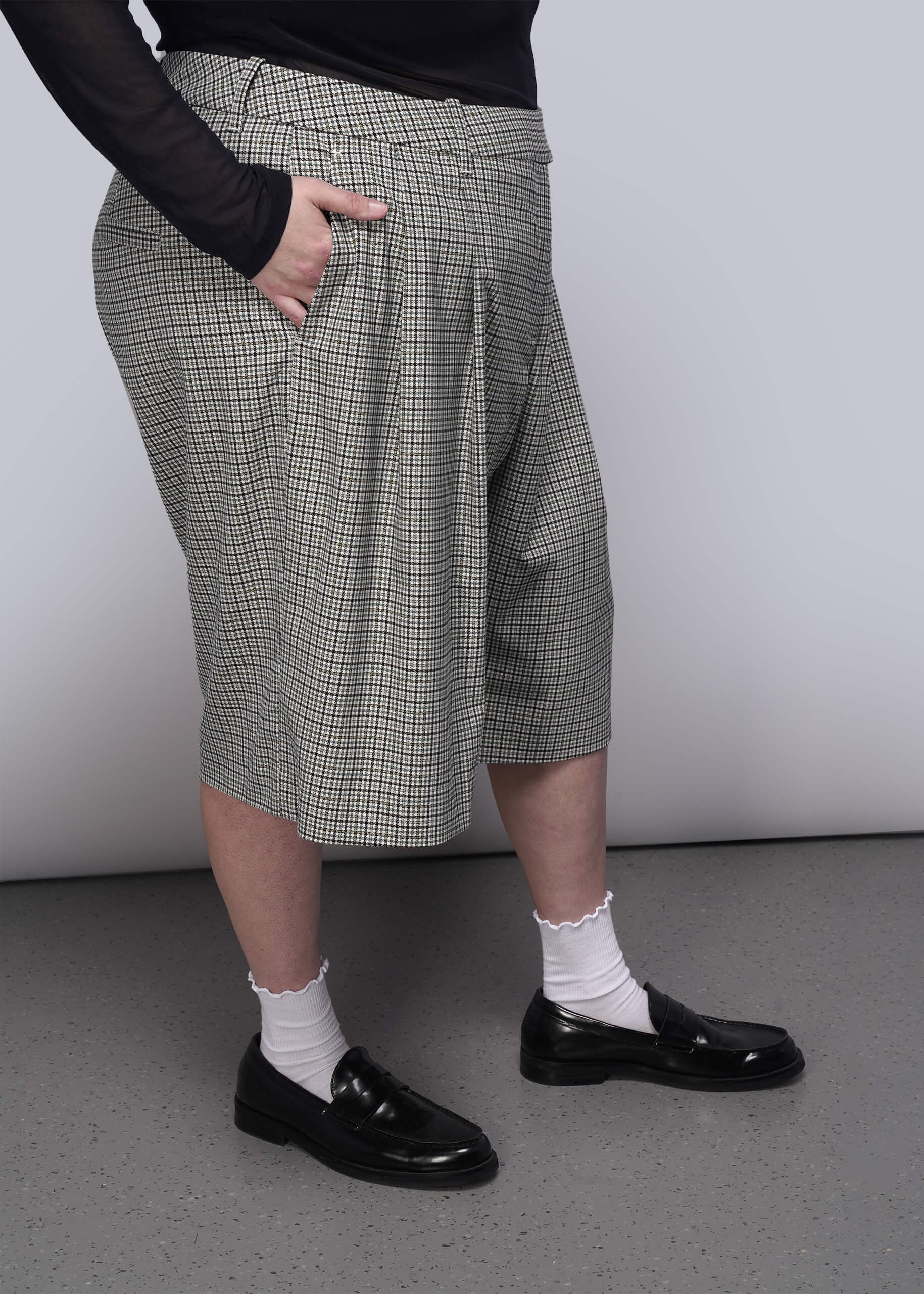 1X=Person wearing plaid shorts, black shoes, and white socks on a plain background