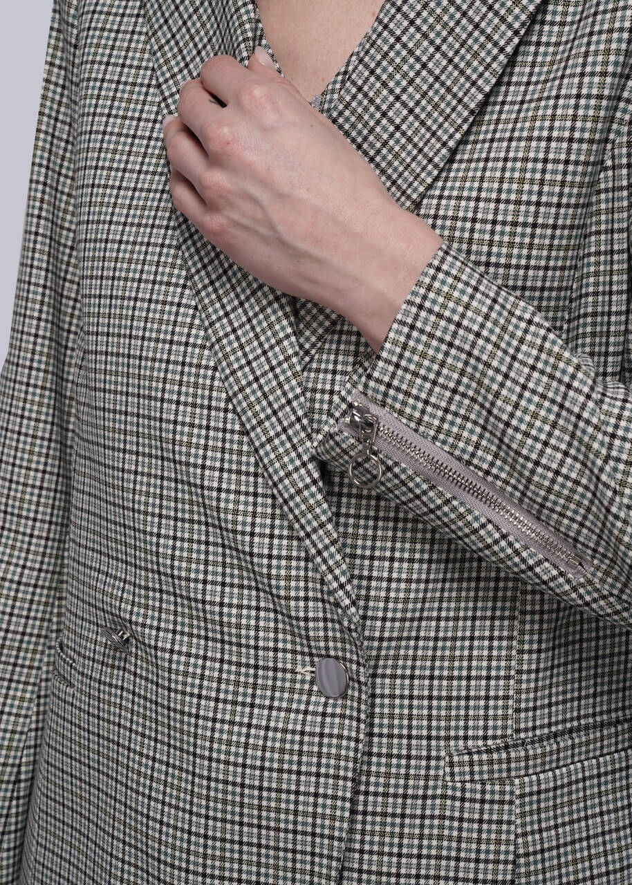 Close-up of a person wearing a checkered blazer with a hand adjusting the collar.