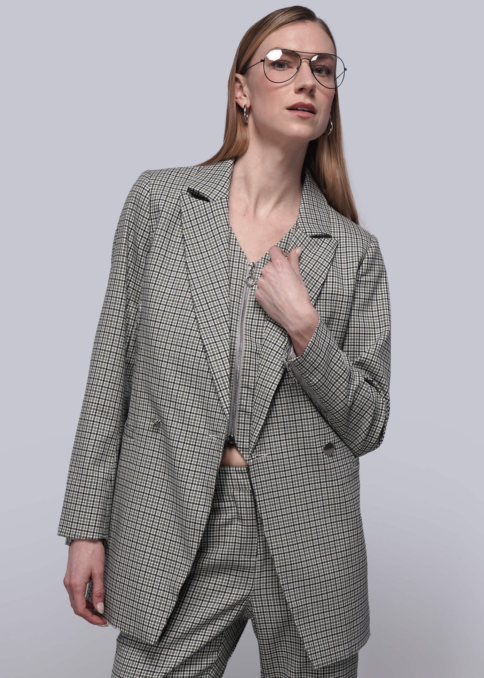 S=Person wearing matching plaid vest, blazer, and trouser against plain background.