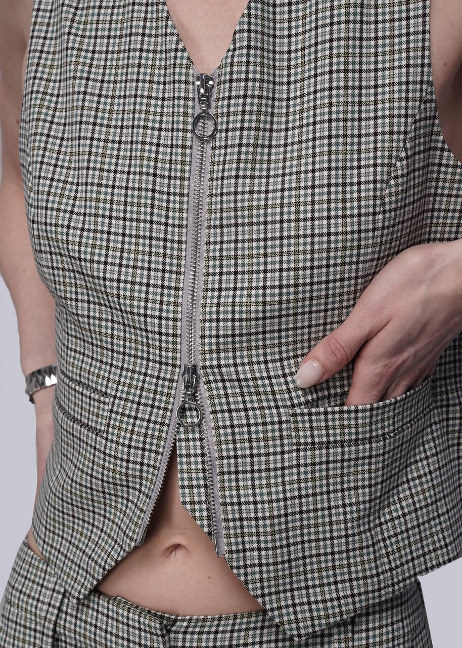 Close up of checkered vest with a zipper detail on a plain background