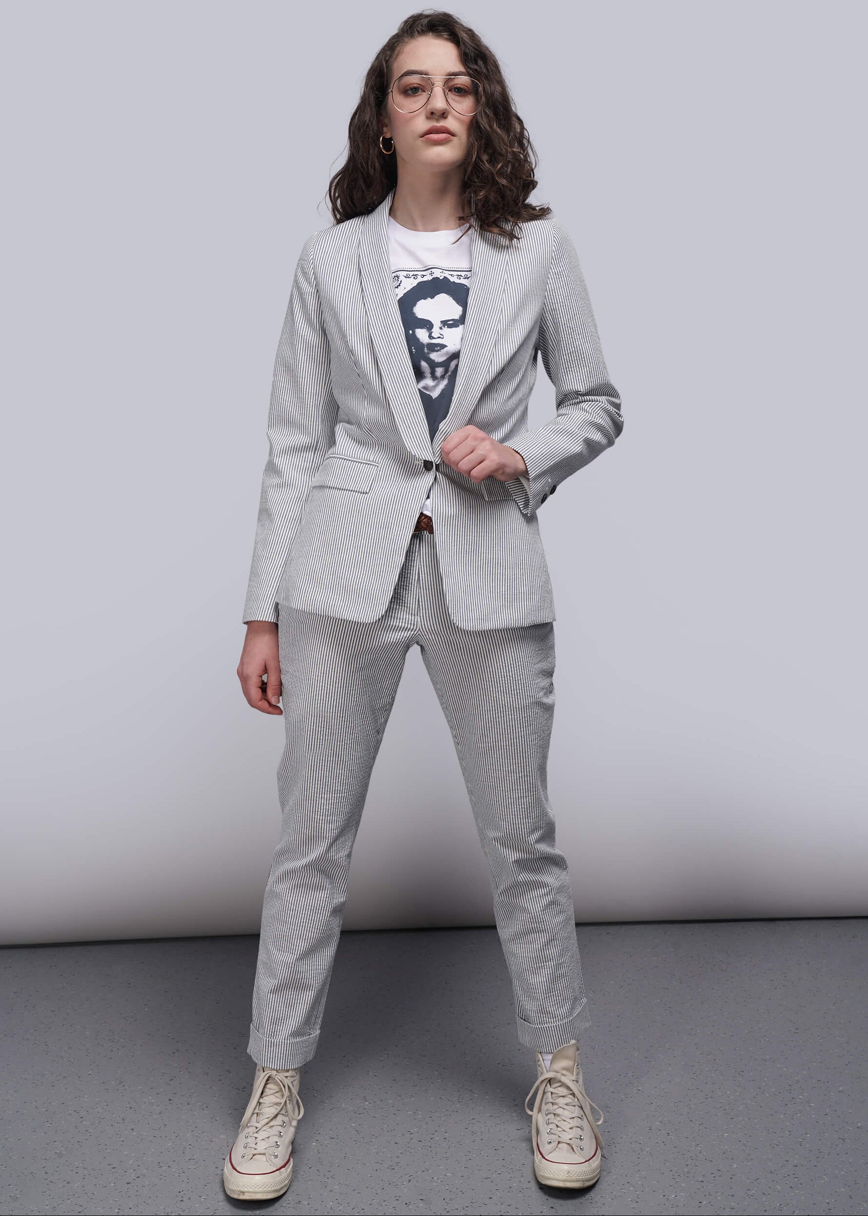 Person wearing a light blue striped seersucker suit with a graphic t-shirt underneath on a plain background