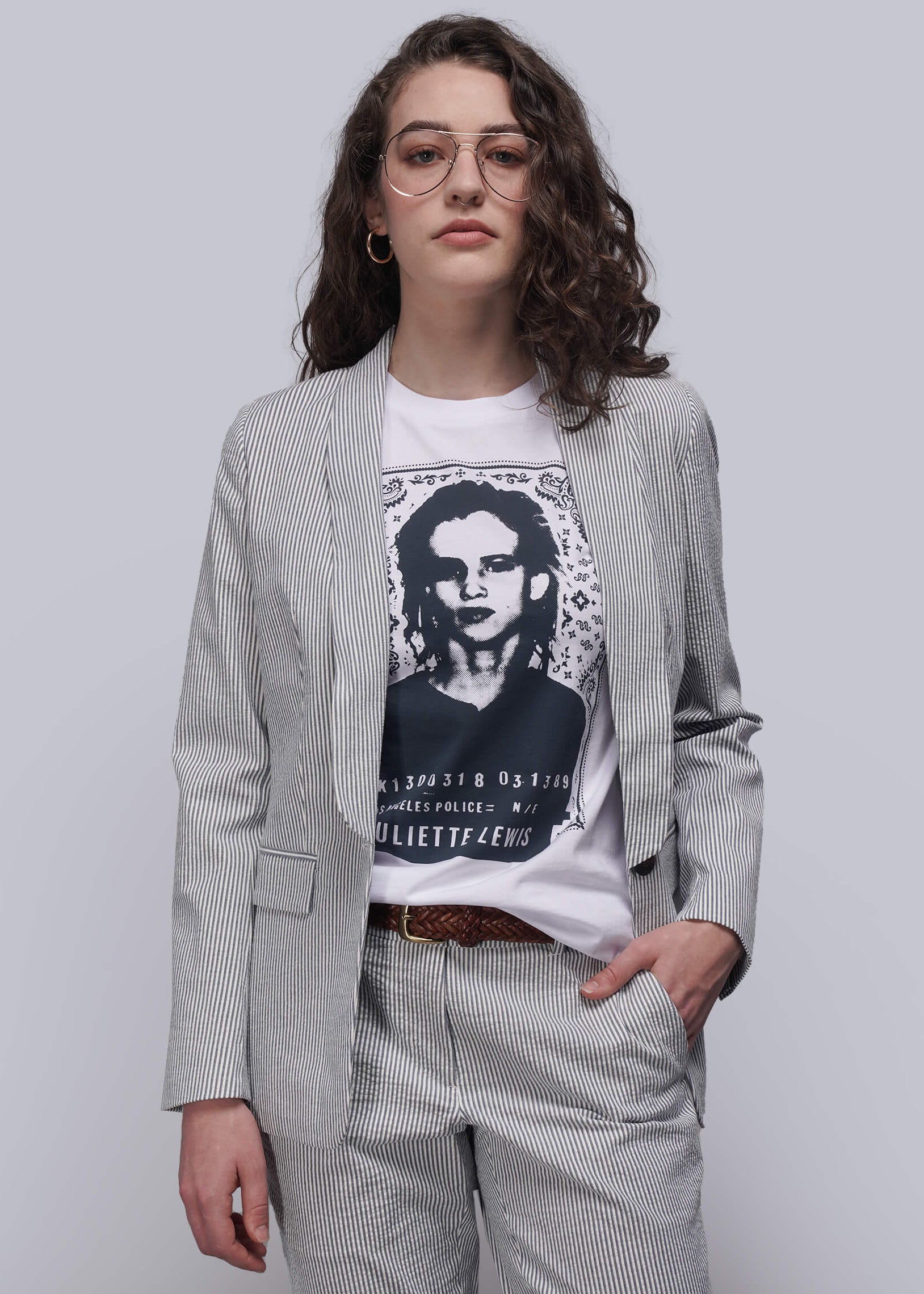 Person wearing a light blue striped seersucker blazer over a graphic t-shirt with a plain background
