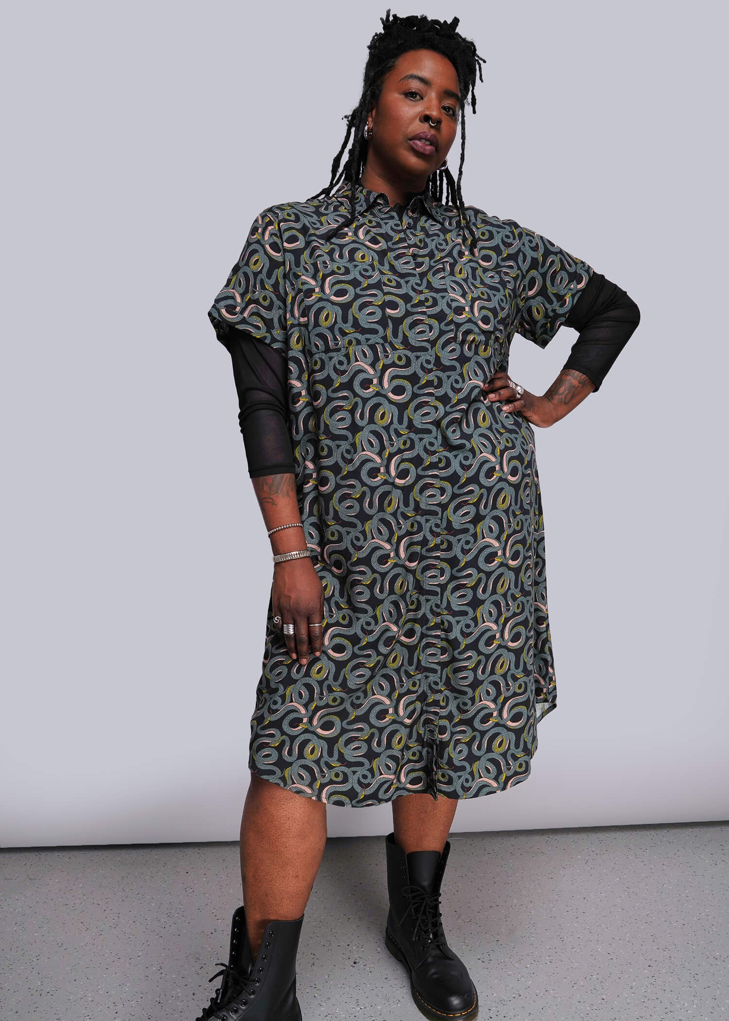 1X=Person wearing a patterned dress with black sleeves against a white background