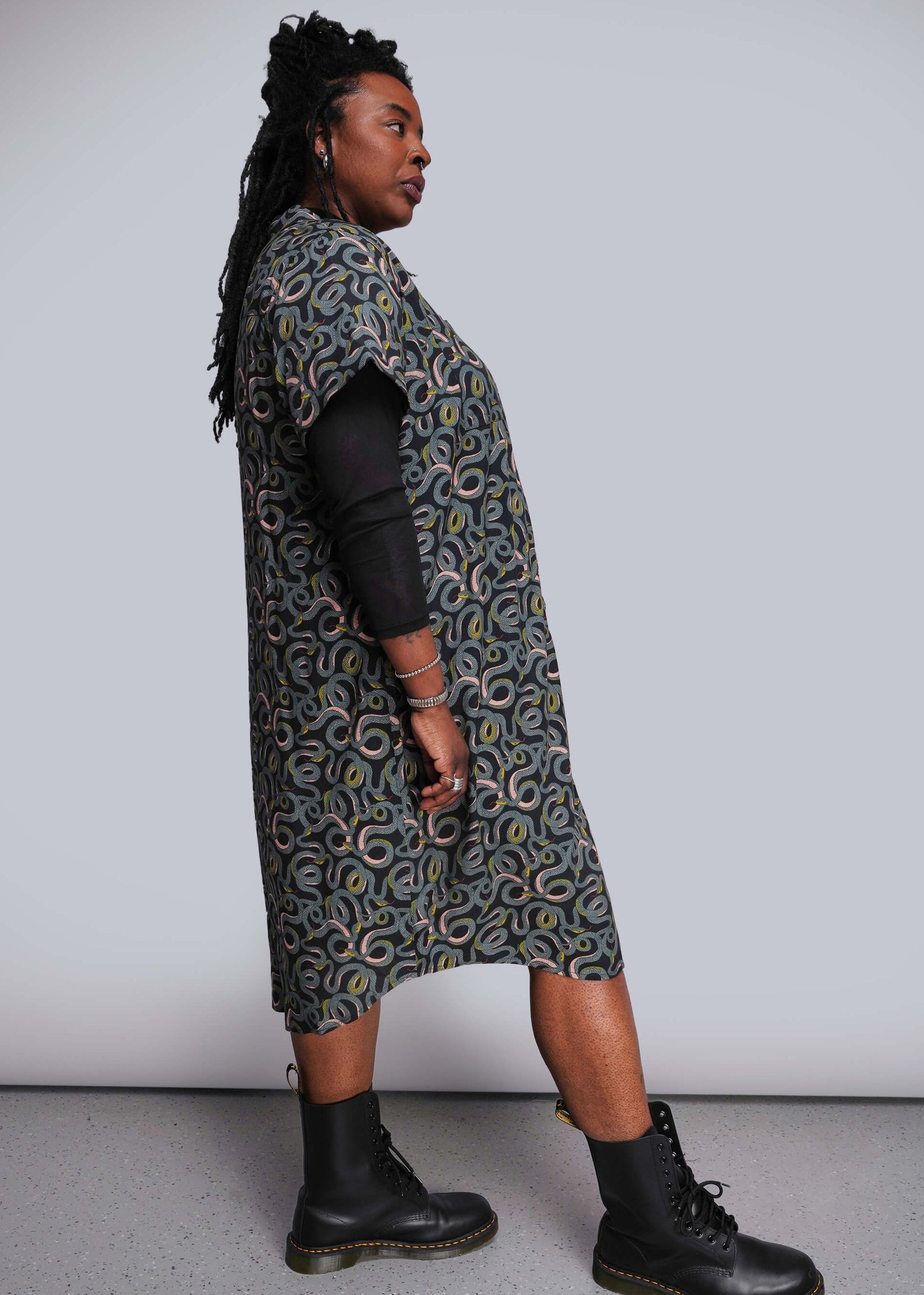 1X=Person wearing a patterned dress with black boots on a plain background