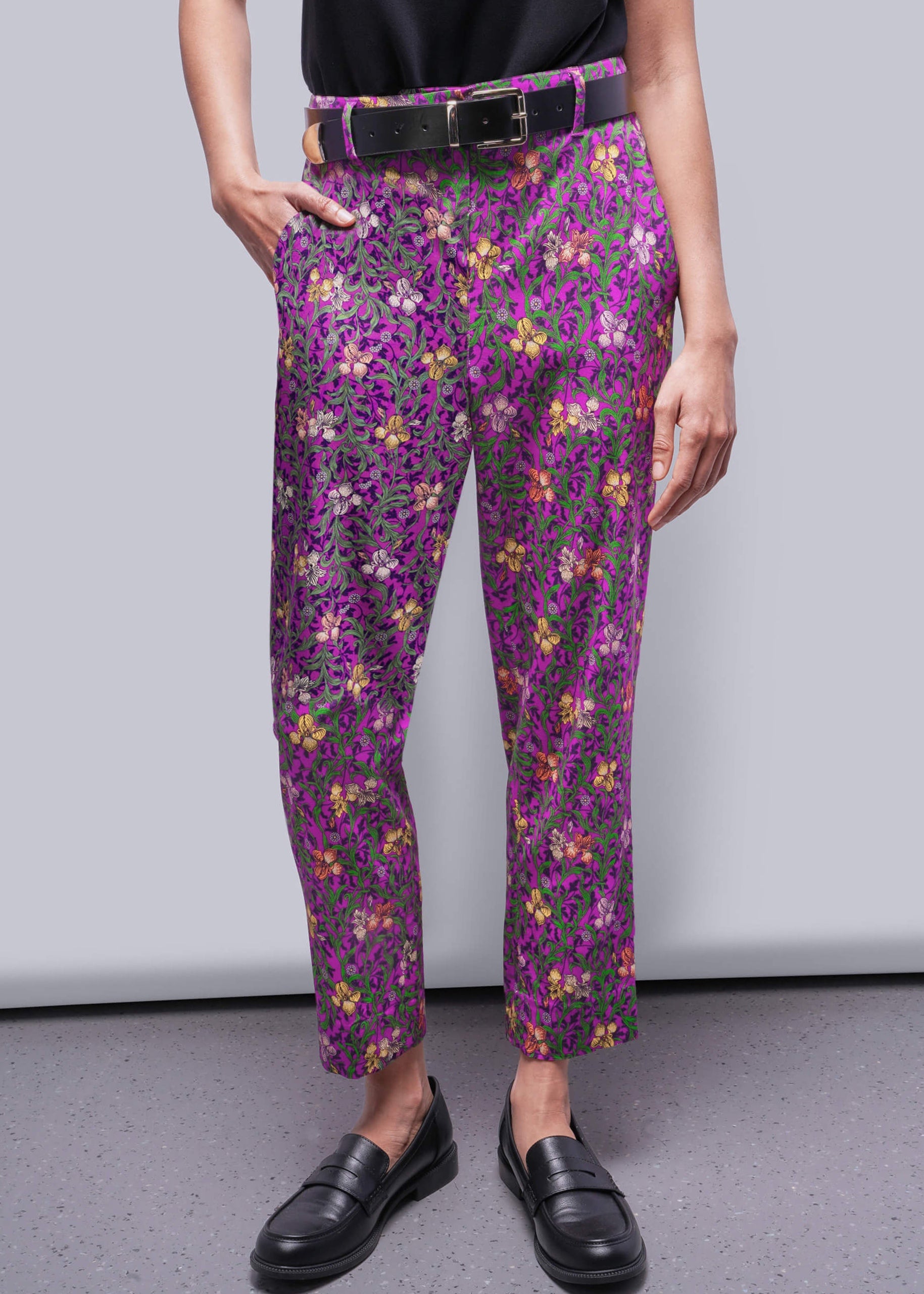Person wearing purple floral pants with a plain background