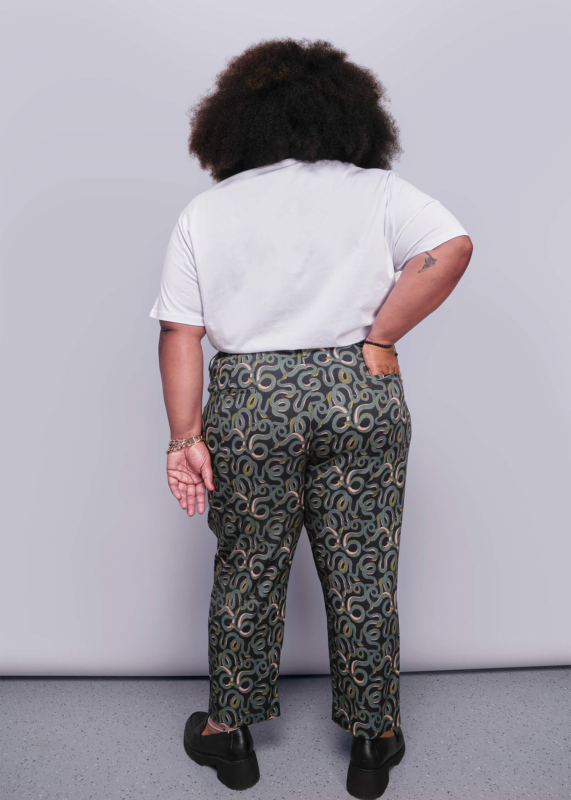 1X=Person wearing a white t-shirt and patterned pants against a plain background