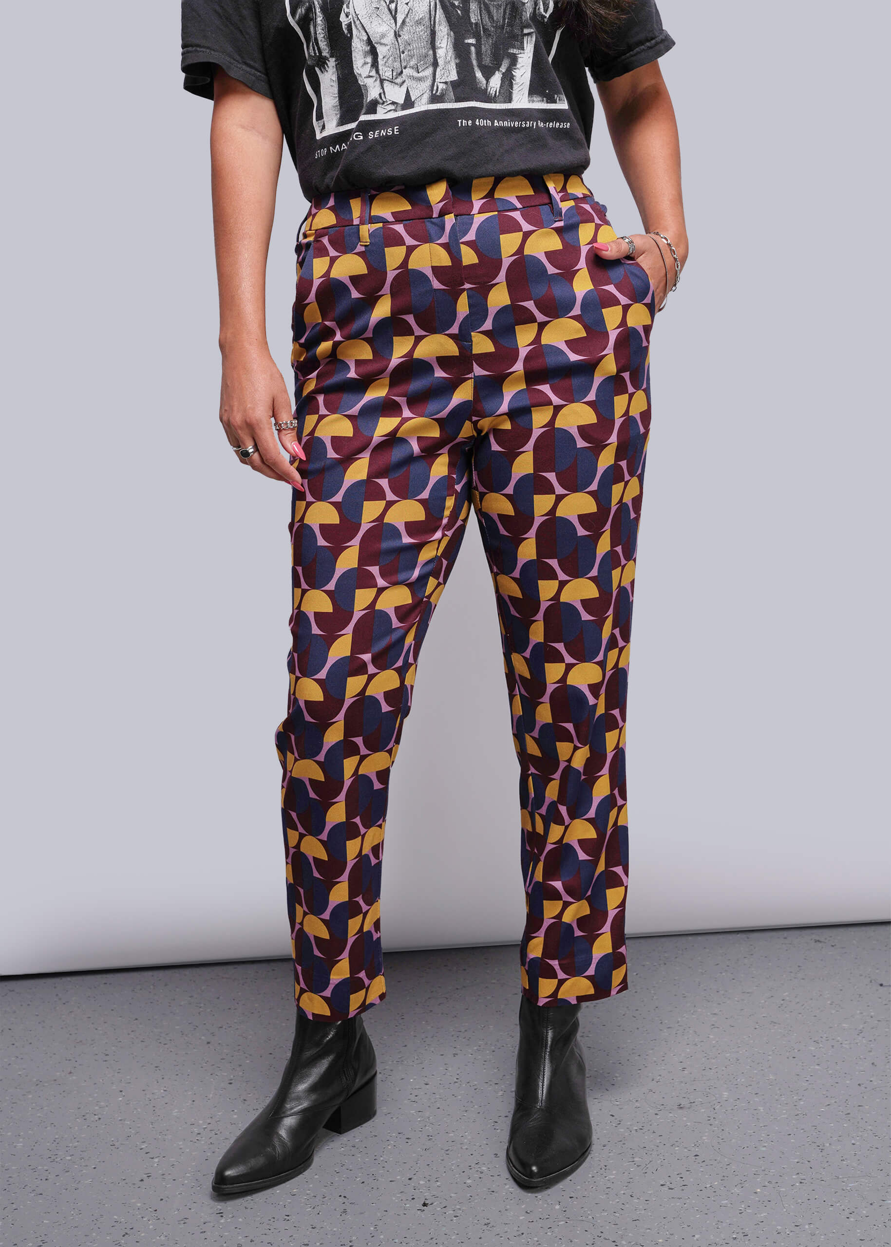 Person wearing colorful geometric-patterned pants with a plain background