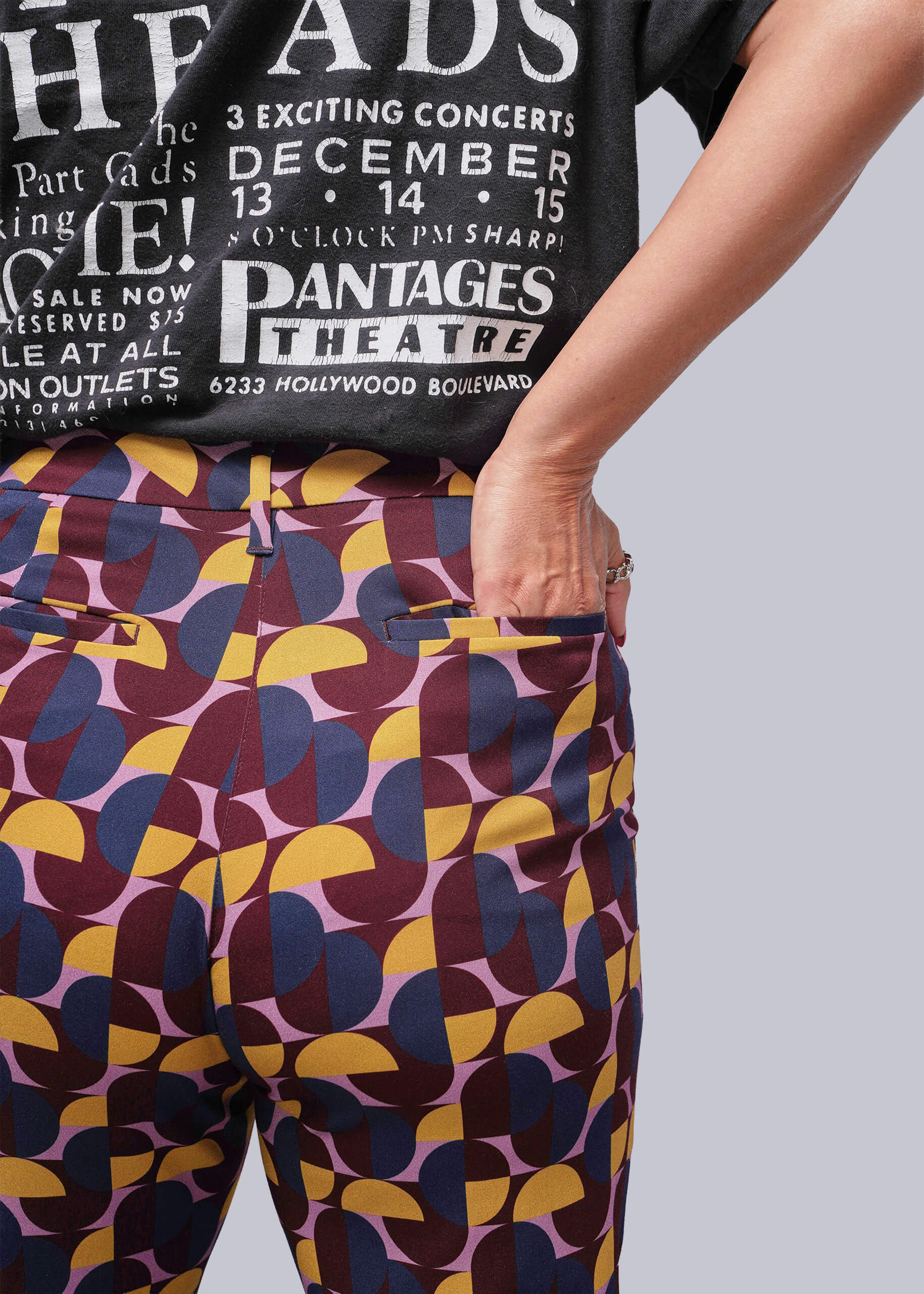 S=Person wearing a black t-shirt with white text and colorful patterned pants.