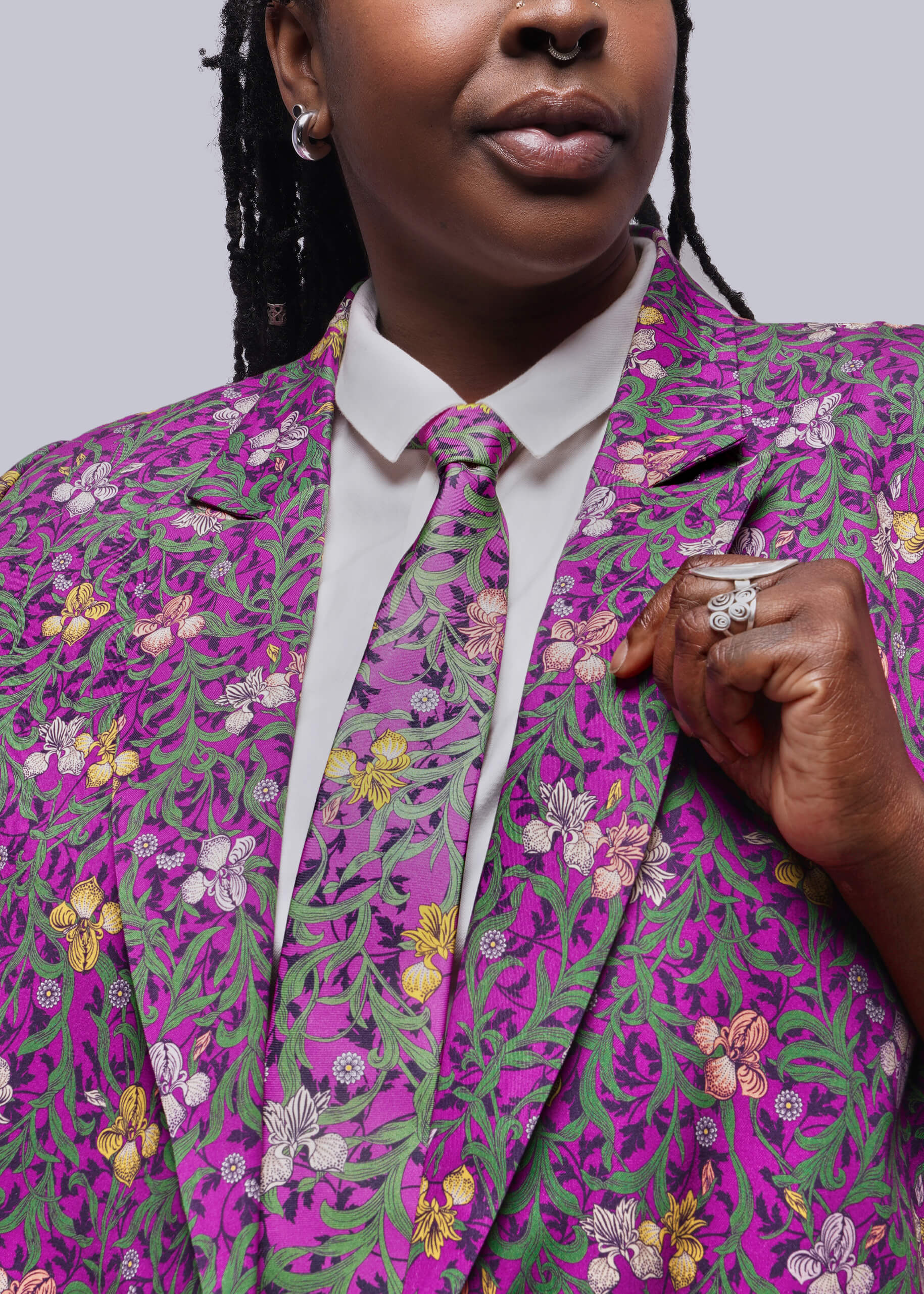 Person wearing a vibrant purple and green floral patterned suit with a white shirt and tie.