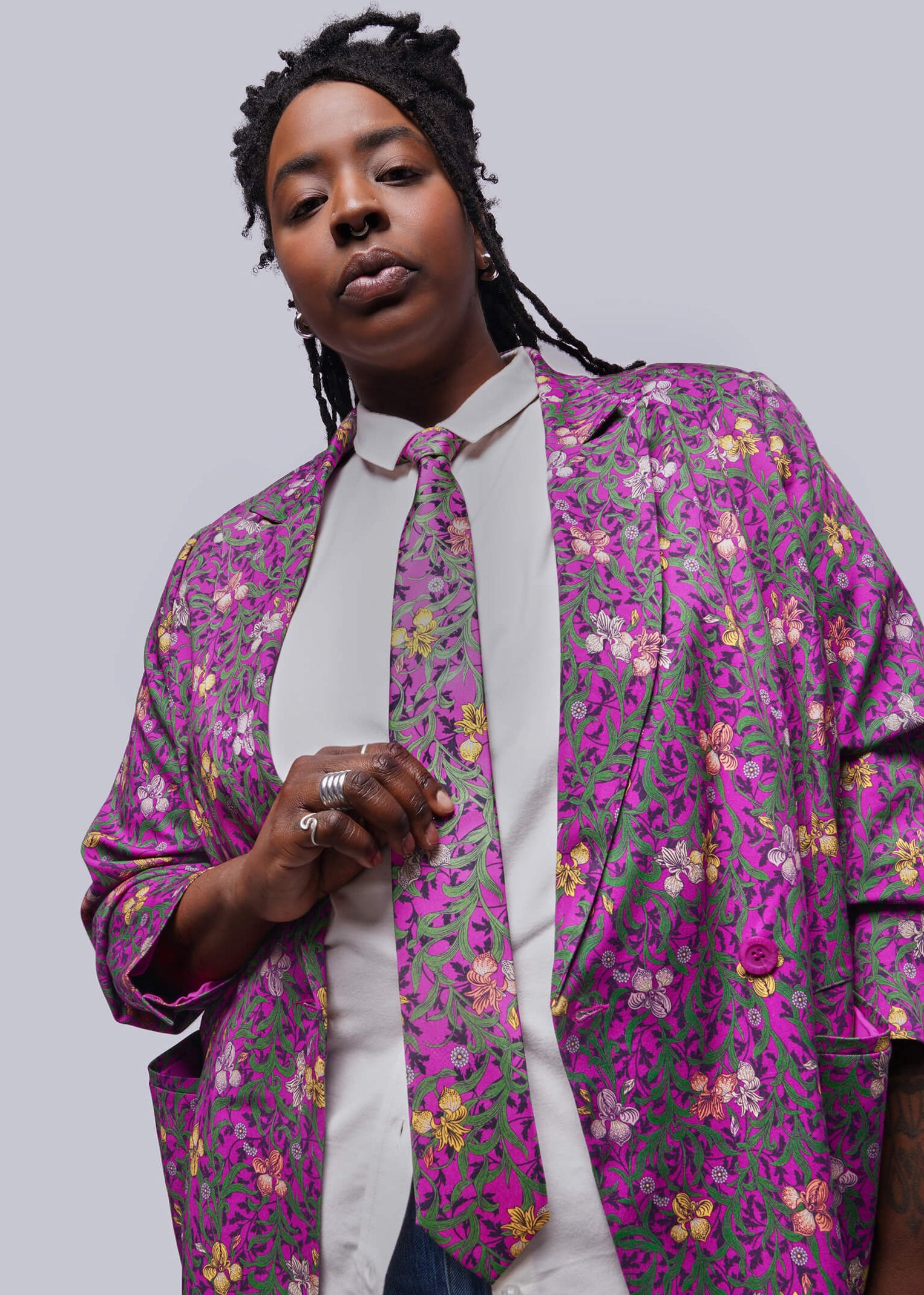 Person wearing a colorful floral-patterned shirt over a white shirt on a plain background