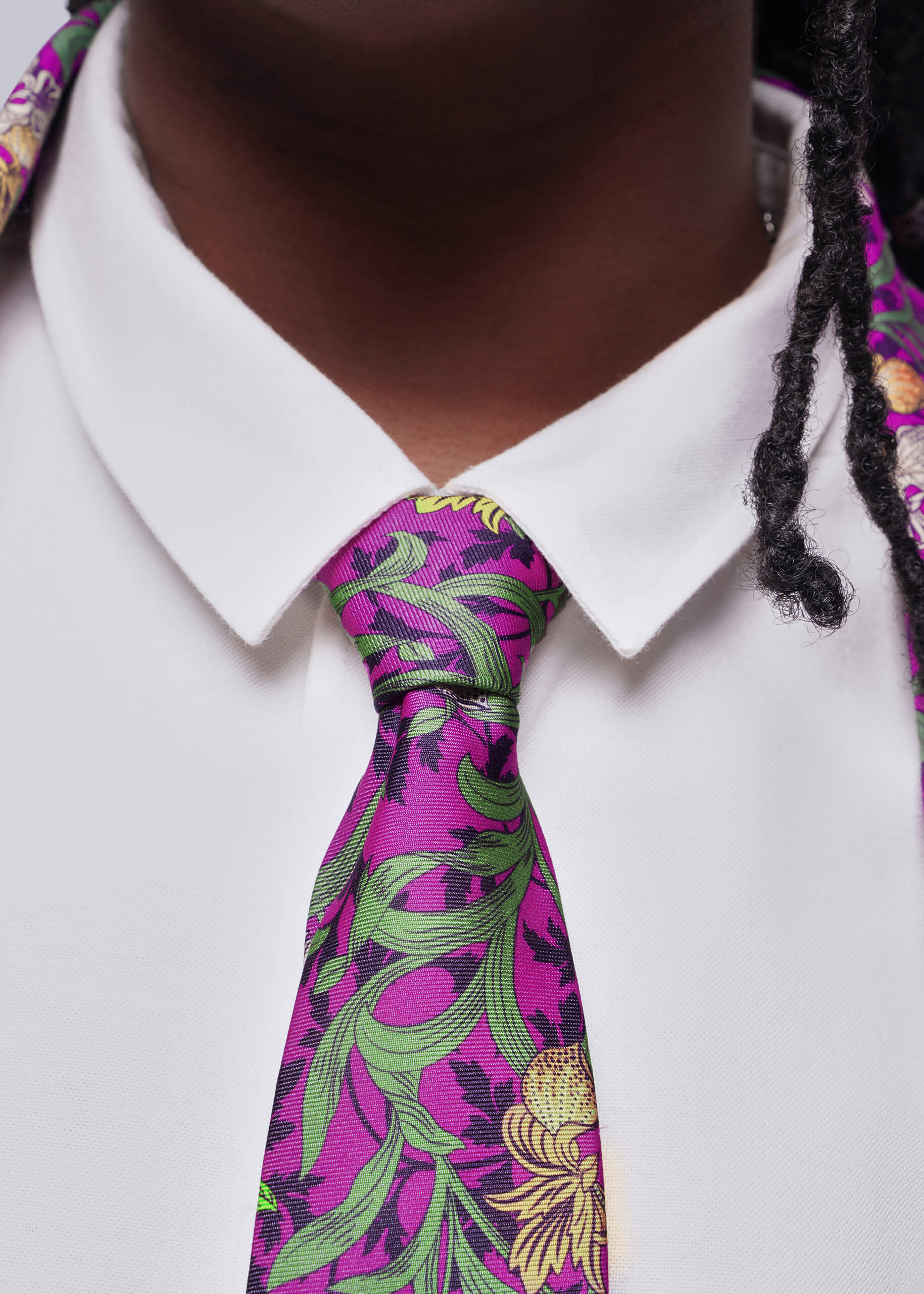 Close up of person wearing a white shirt with a colorful floral tie.