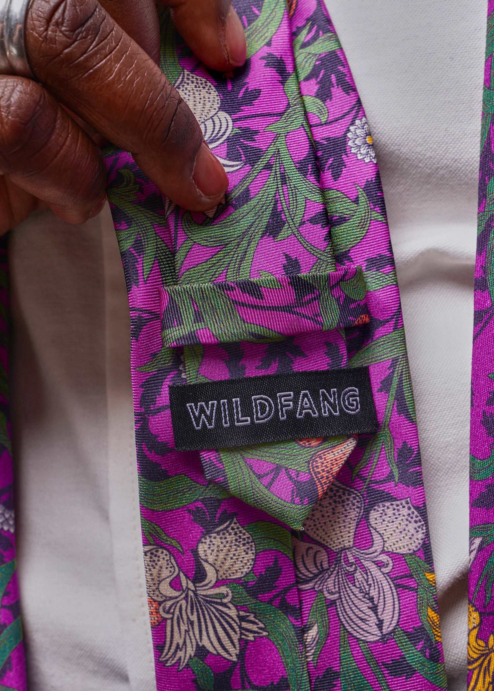 Floral-patterned tie with 'WILDFANG' label held by a hand