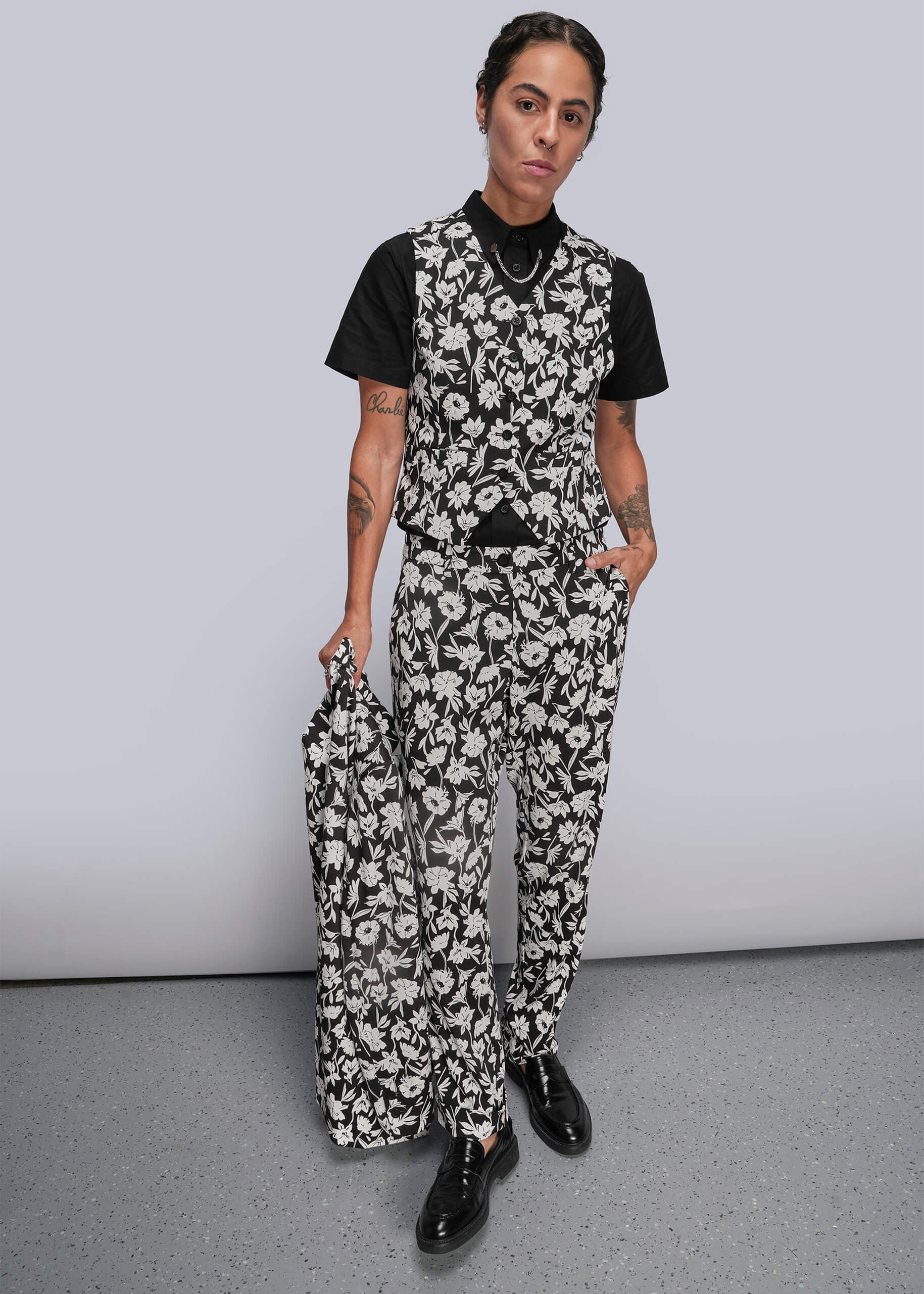 Person wearing a black and white floral suit with a plain background