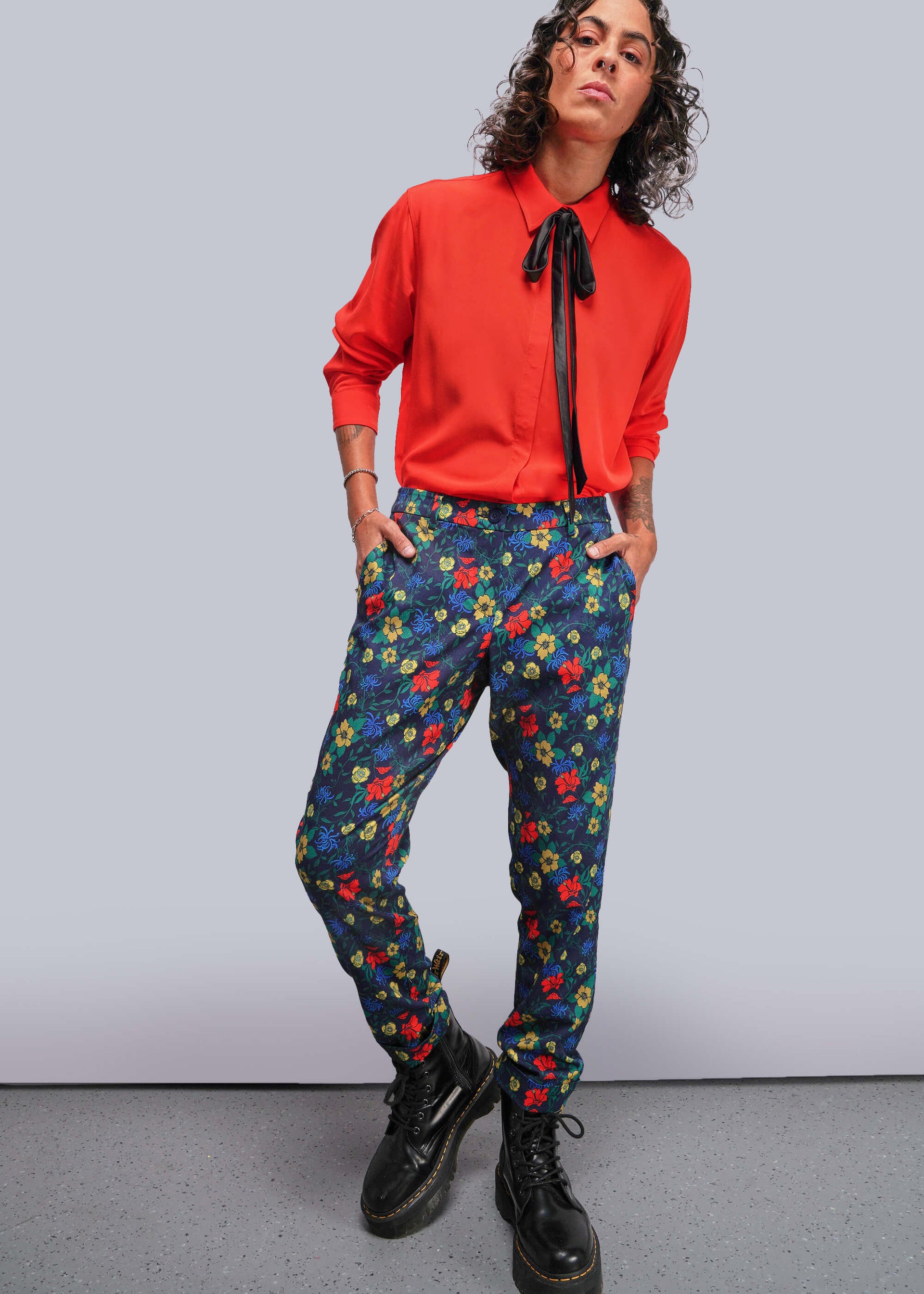 S=Person wearing a red shirt and colorful floral pants against a plain background