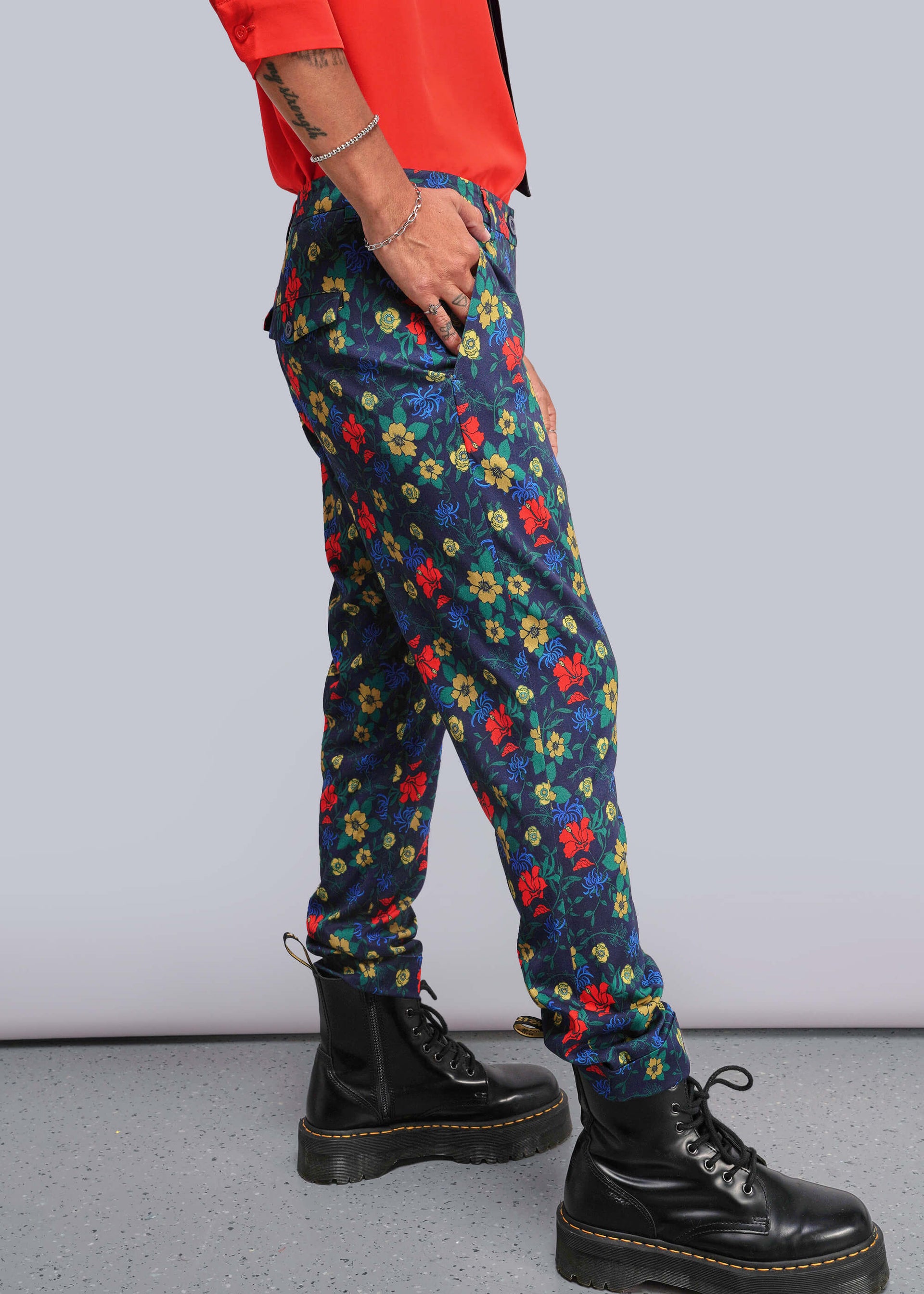 S=Person wearing colorful floral pants and black boots on a plain background