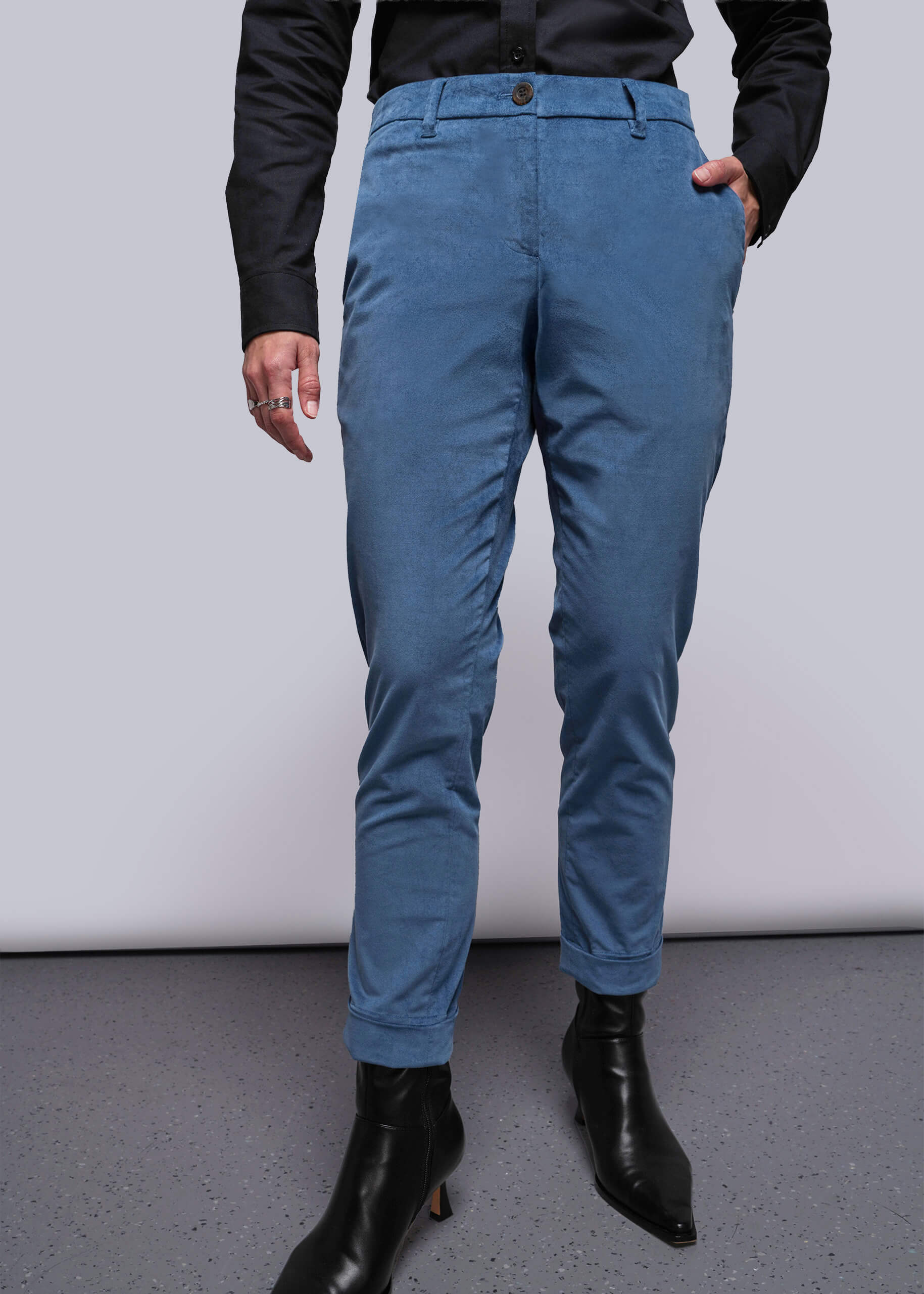 Person wearing blue pants and black boots on a plain background