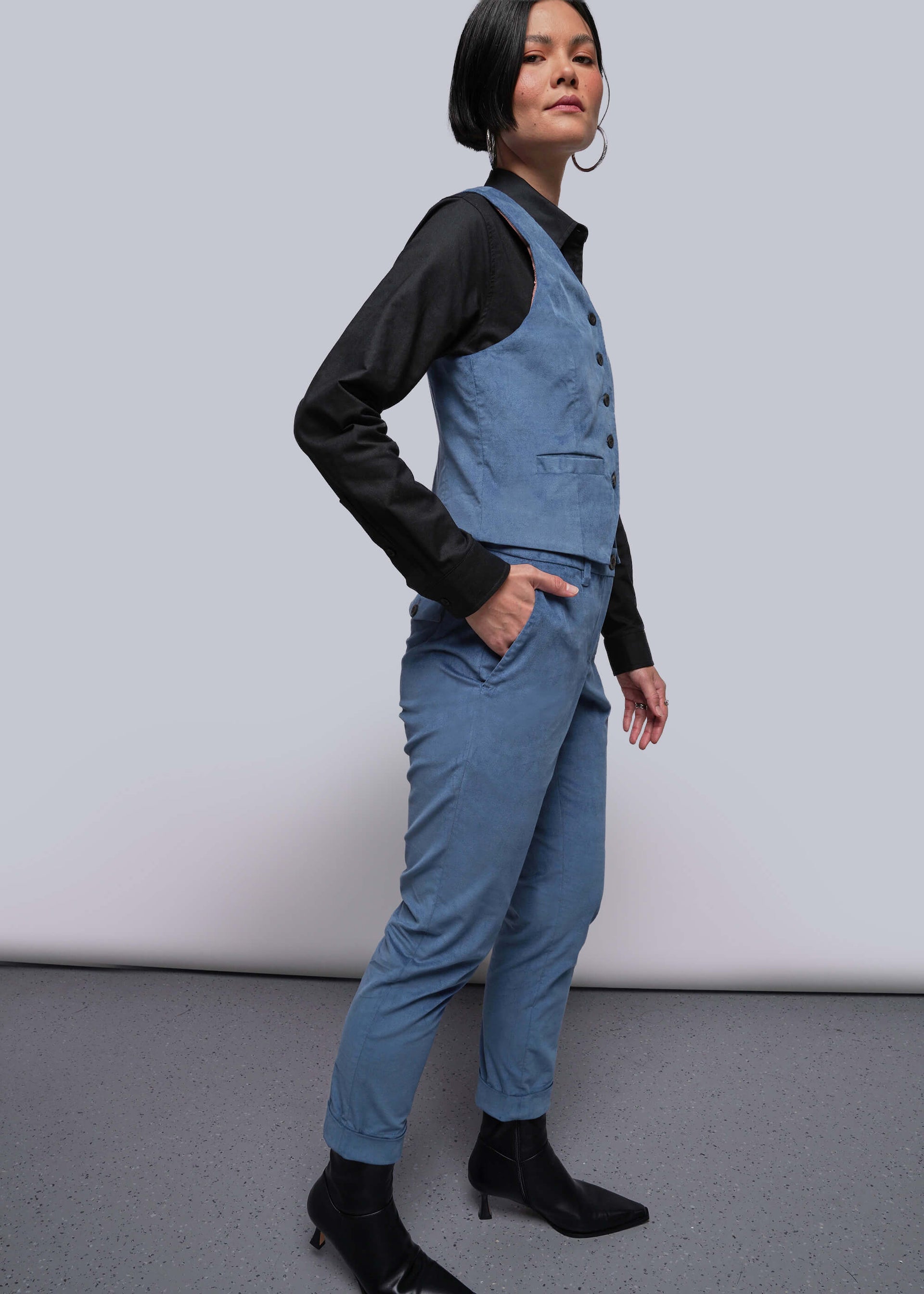 S=Person wearing a blue jumpsuit with a black shirt underneath on a plain background
