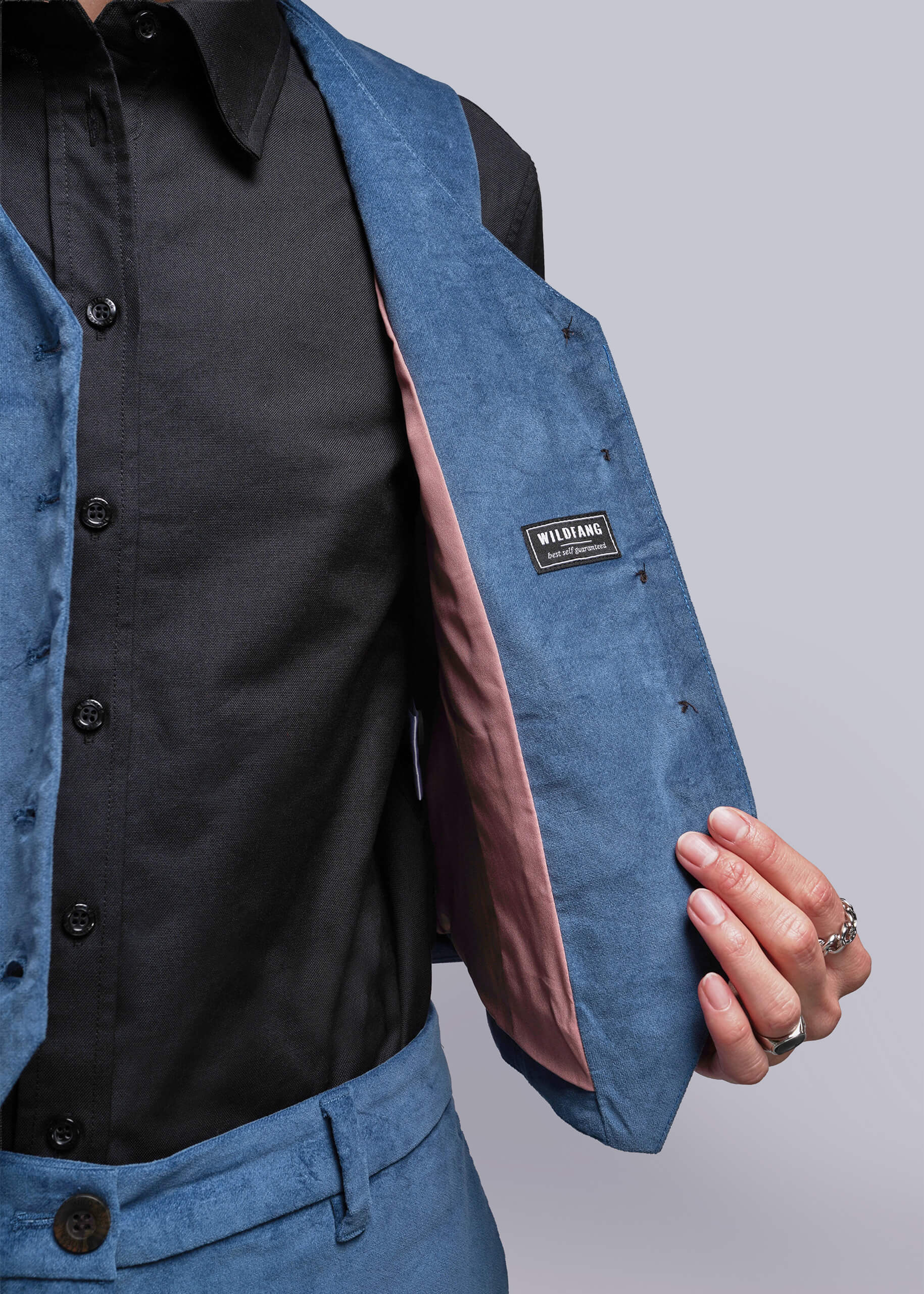 S=Close-up of a person wearing a blue vest with a visible brand label on a plain background