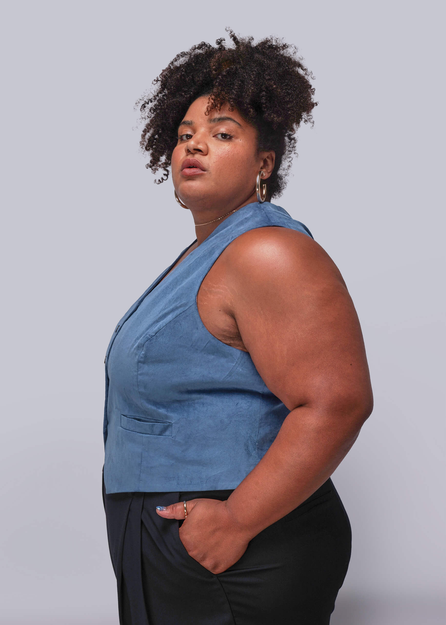 1X=Person wearing a blue sleeveless top against a plain background