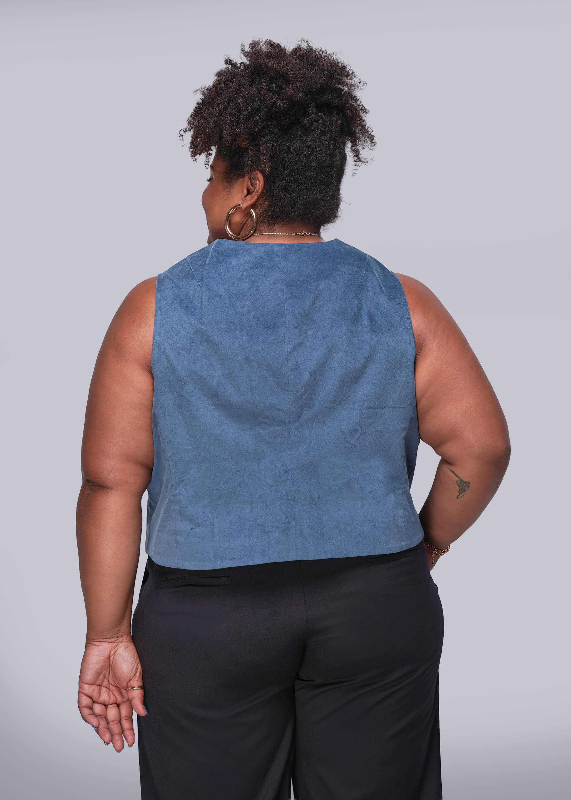 1X=Person wearing a blue velvet vest and black pants against a plain background