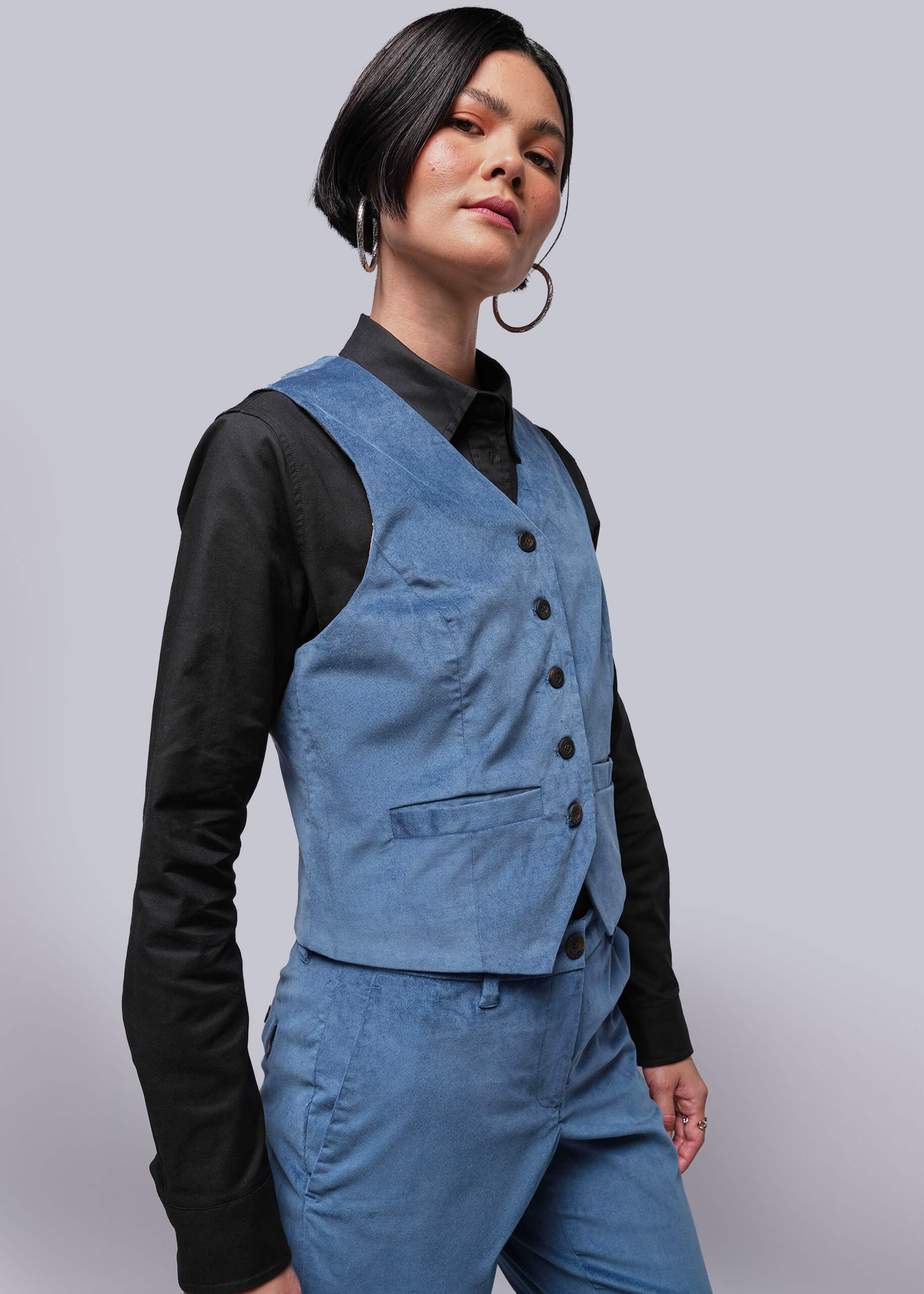 S=Person wearing a blue vest over a black shirt on a plain background