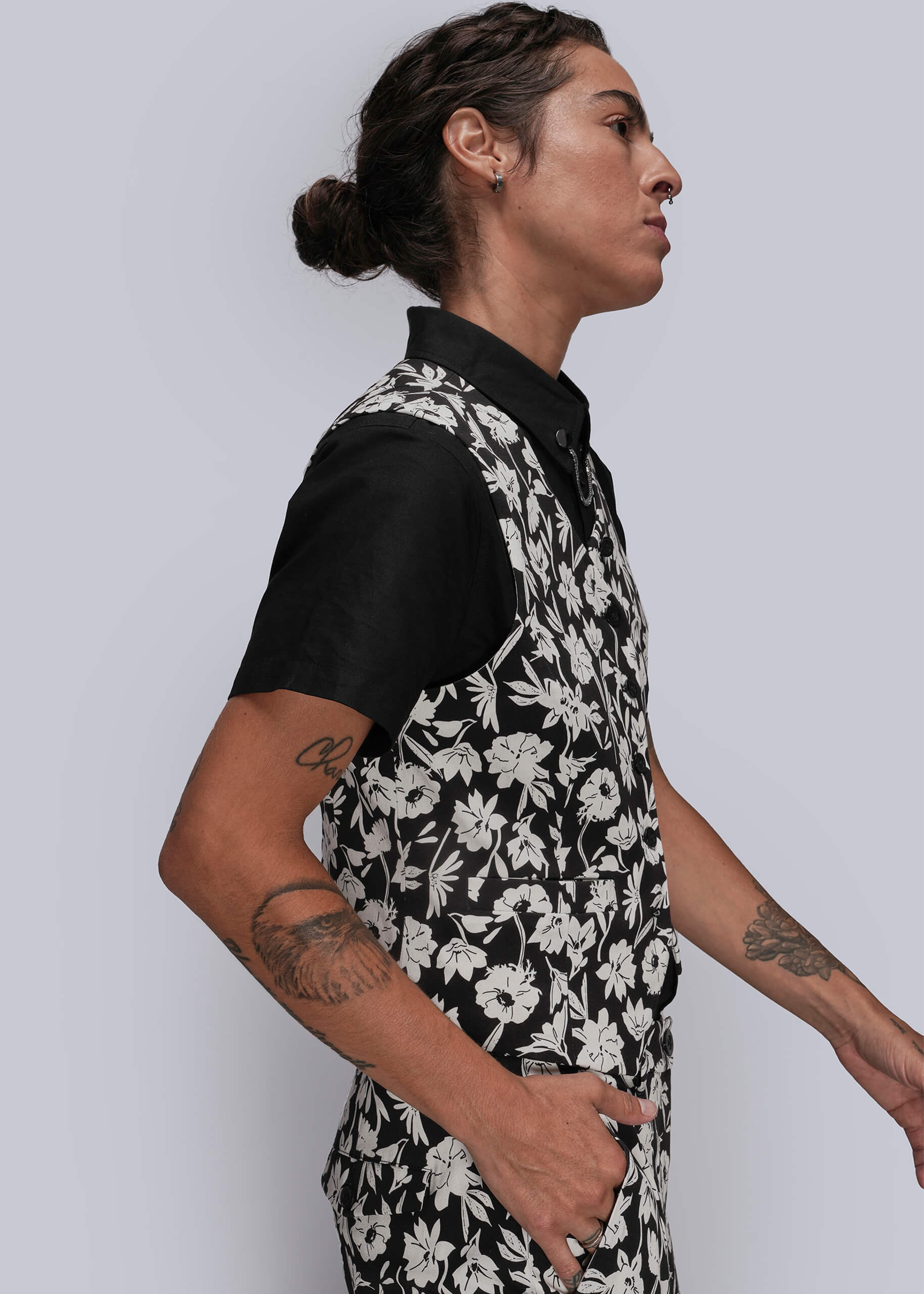 S=Person wearing a black and white floral vest against a plain background
