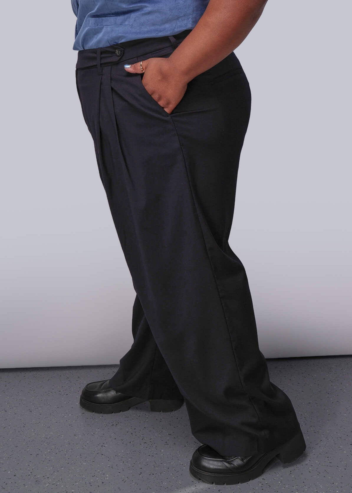 1X=Person wearing a blue sleeveless top and black pants against a plain background