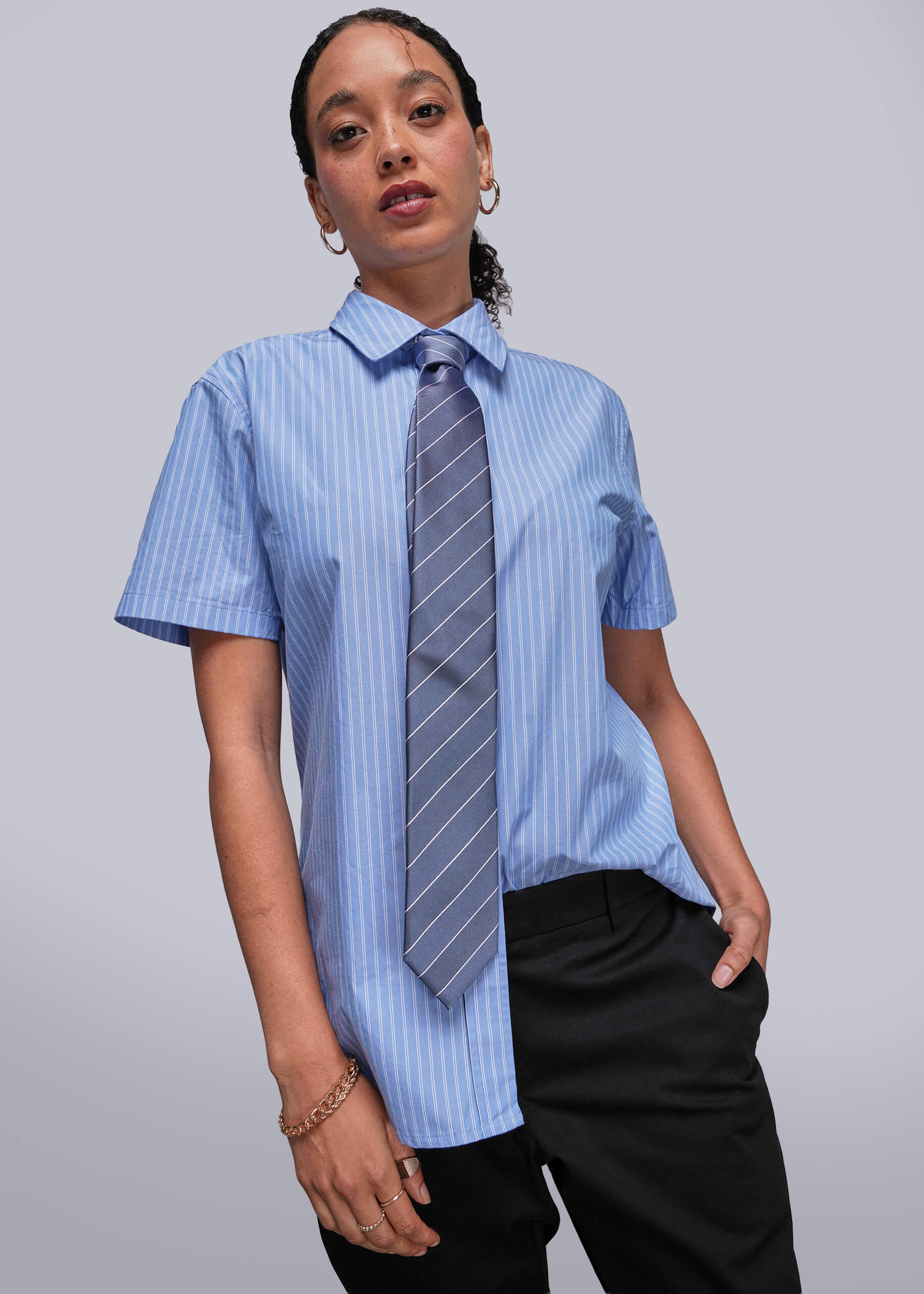 Person wearing a blue striped shirt with a tie against a plain background